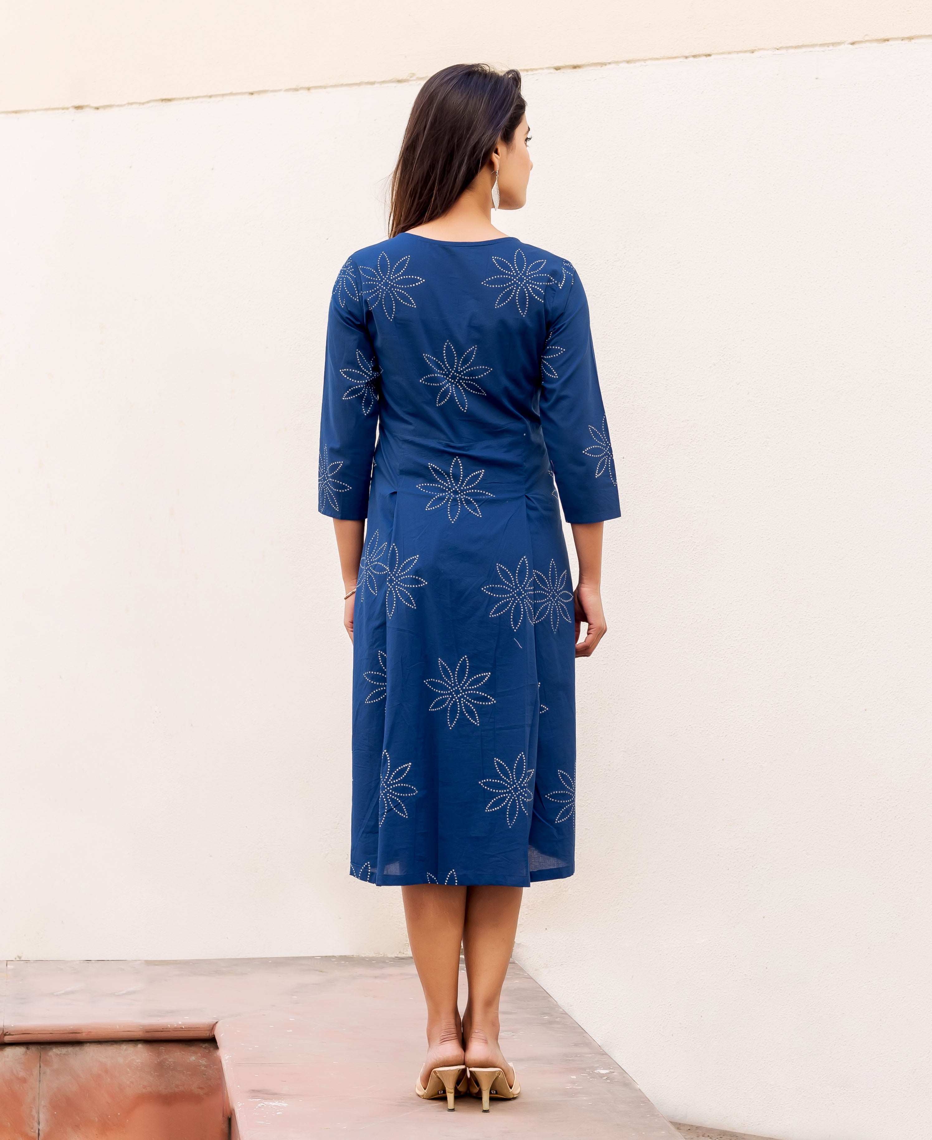 Back view model in indigo hand-block-printed dress with white dotted floral patterns.