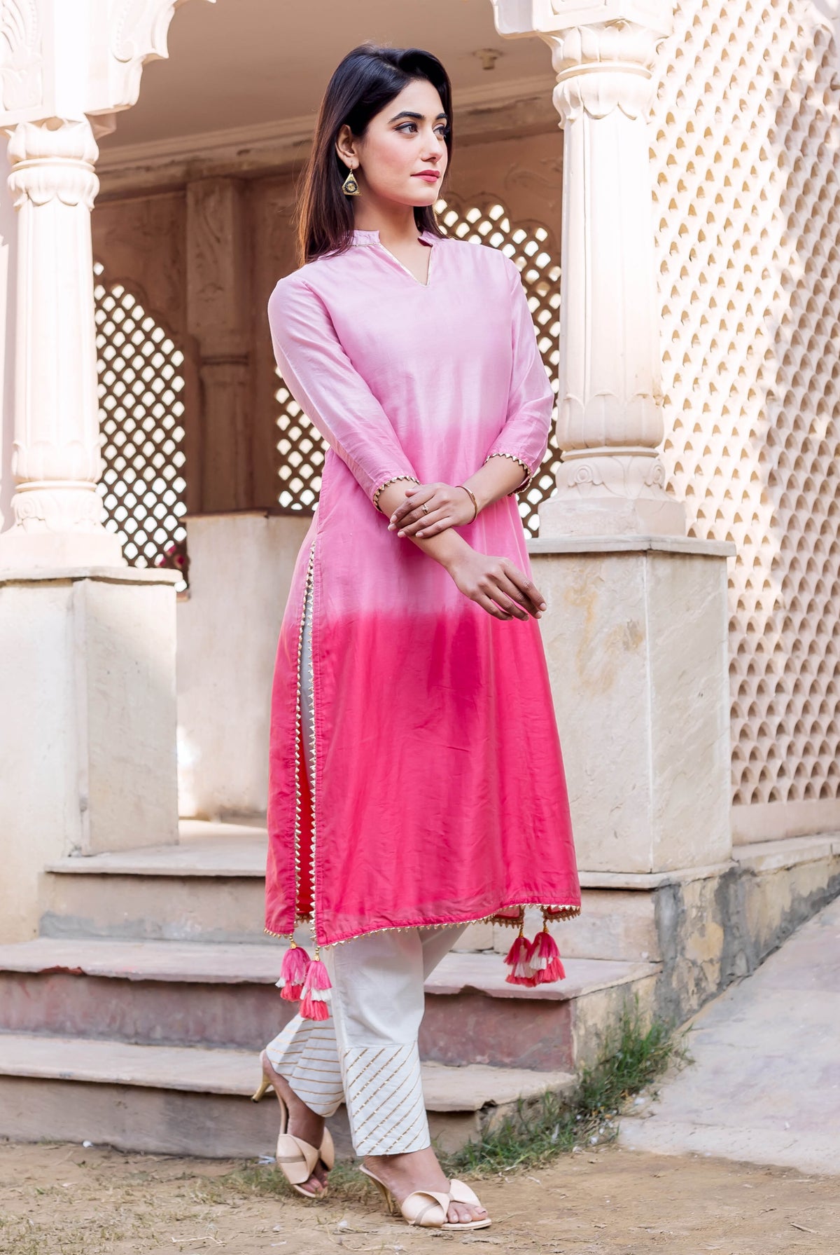 Full shot of model wearing an ombre pink kurta with white pants and golden striped print.