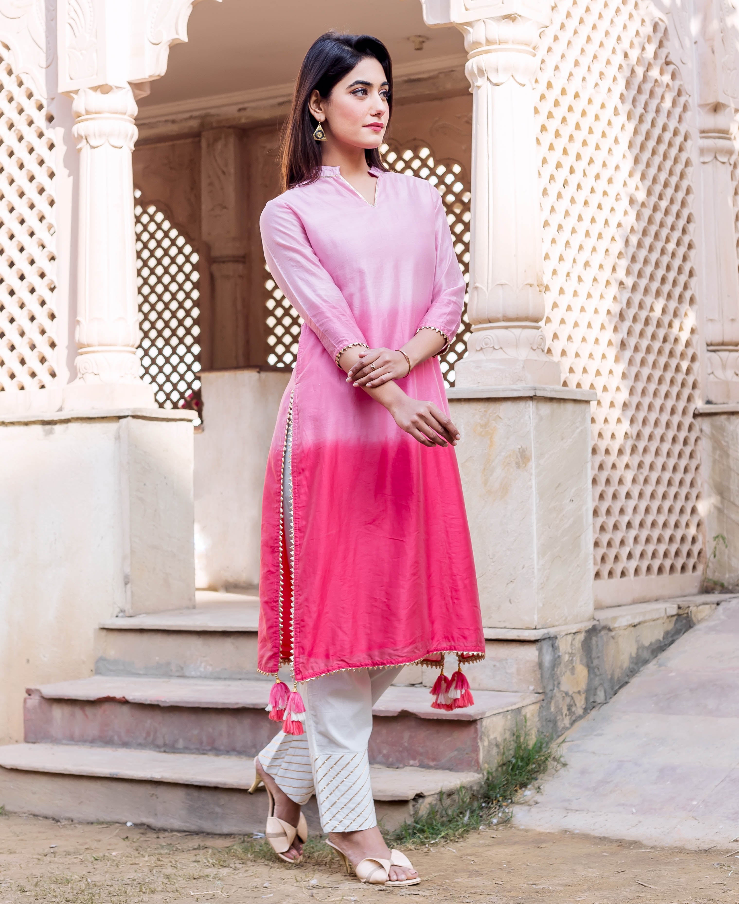 Full shot of model wearing an ombre pink kurta with white pants and golden striped print.