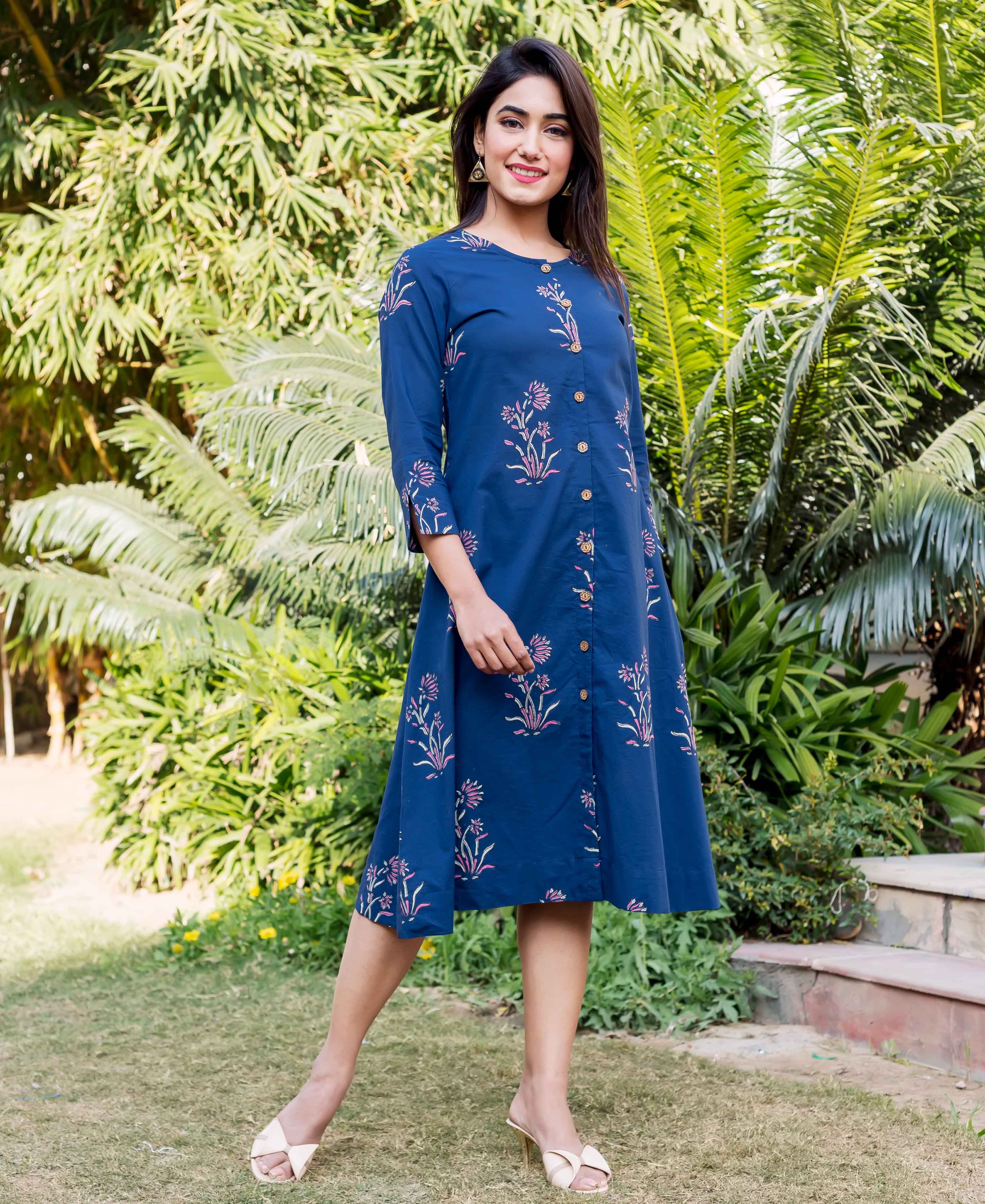 Model wears indigo knee-length dress featuring hand-block printed pink and green floral designs.