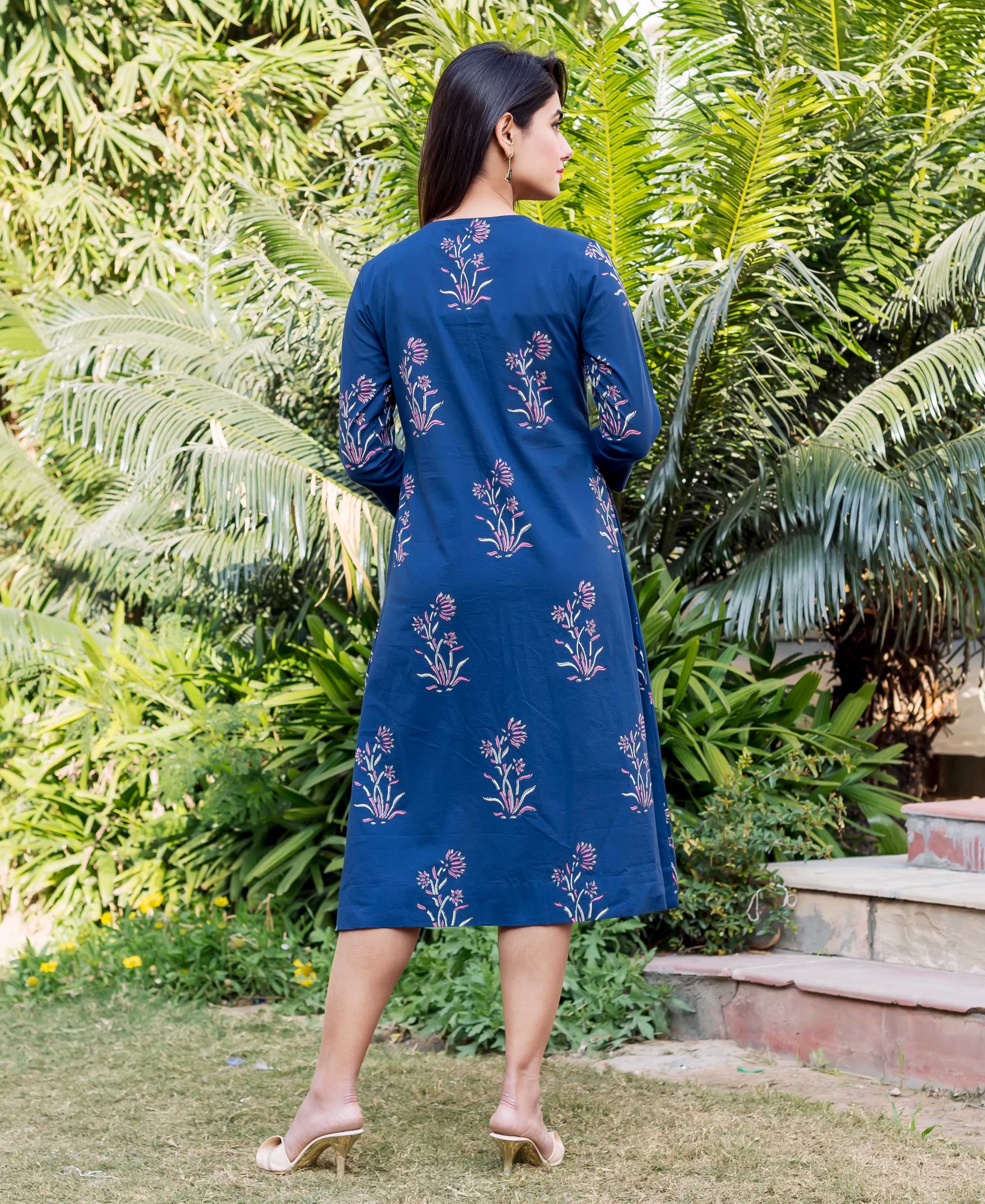 Back of model in indigo block printed knee-length dress with pink floral design.