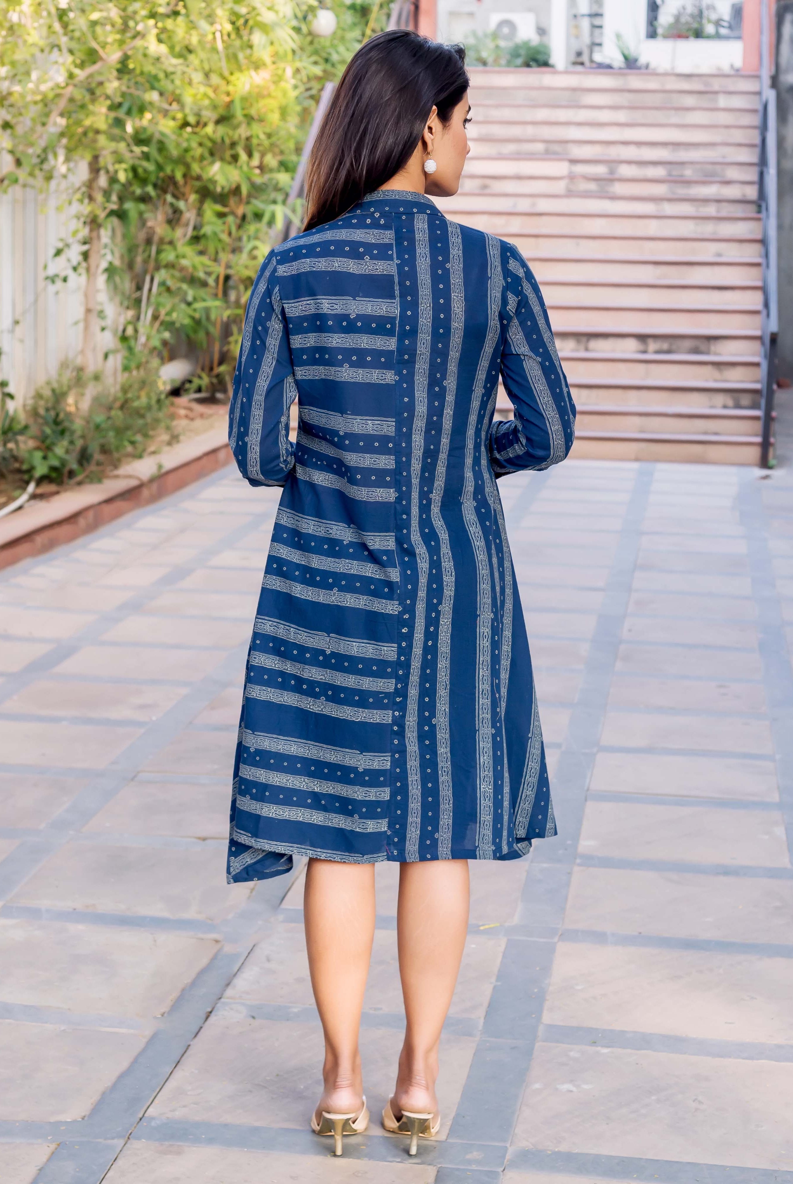 A woman wearing a blue and white block-printed dress with a high-low hem.