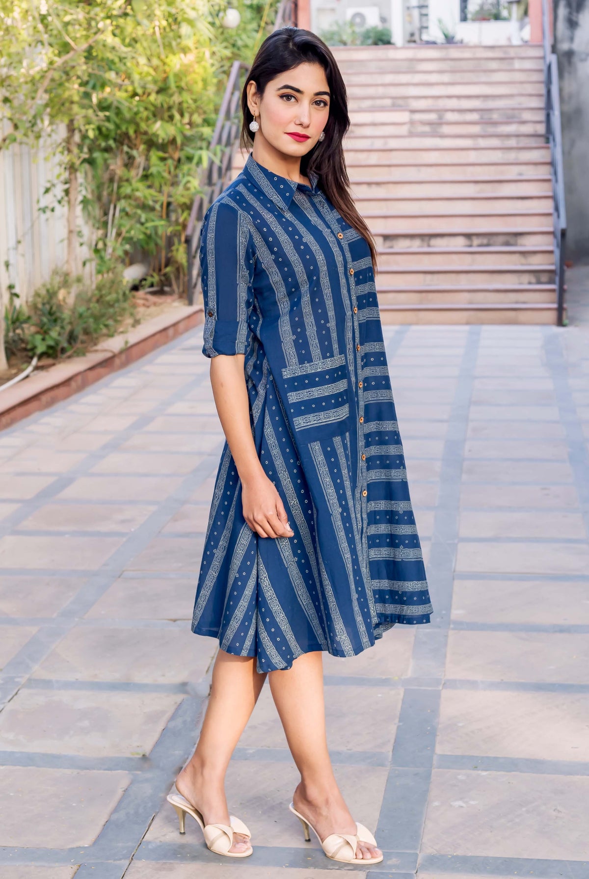 Model wearing an indigo blue button-down dress with varied block printed patterns.