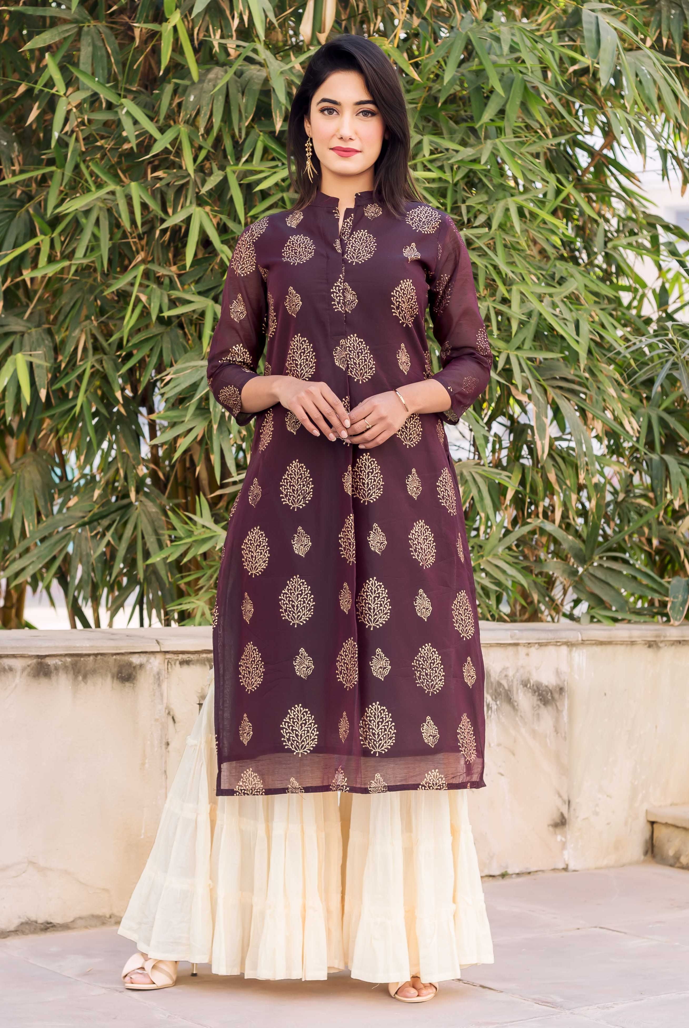 Model wearing wine gold block print kurti and creme tiered sharara.