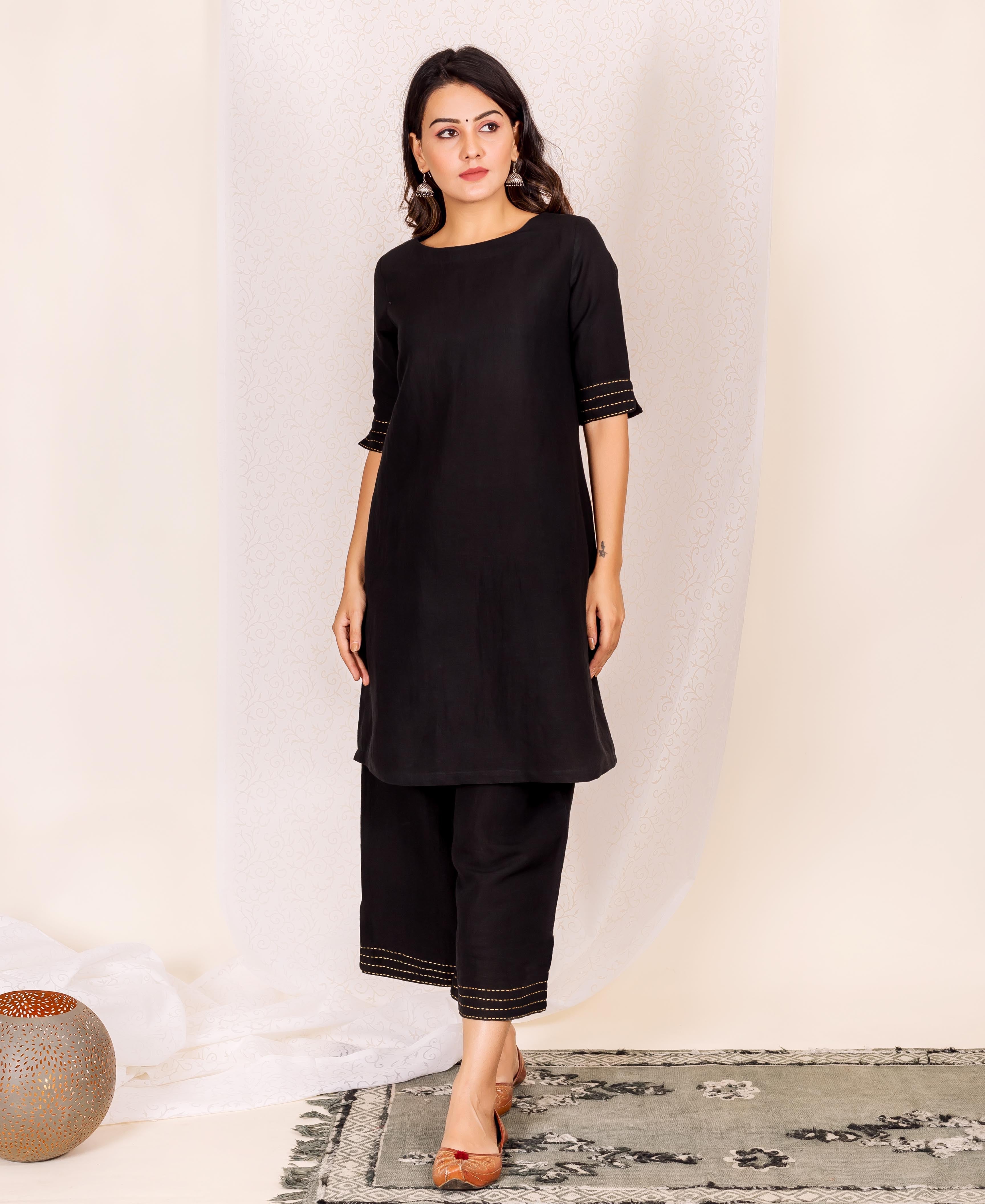 A woman models a black linen kurta with gold accents.