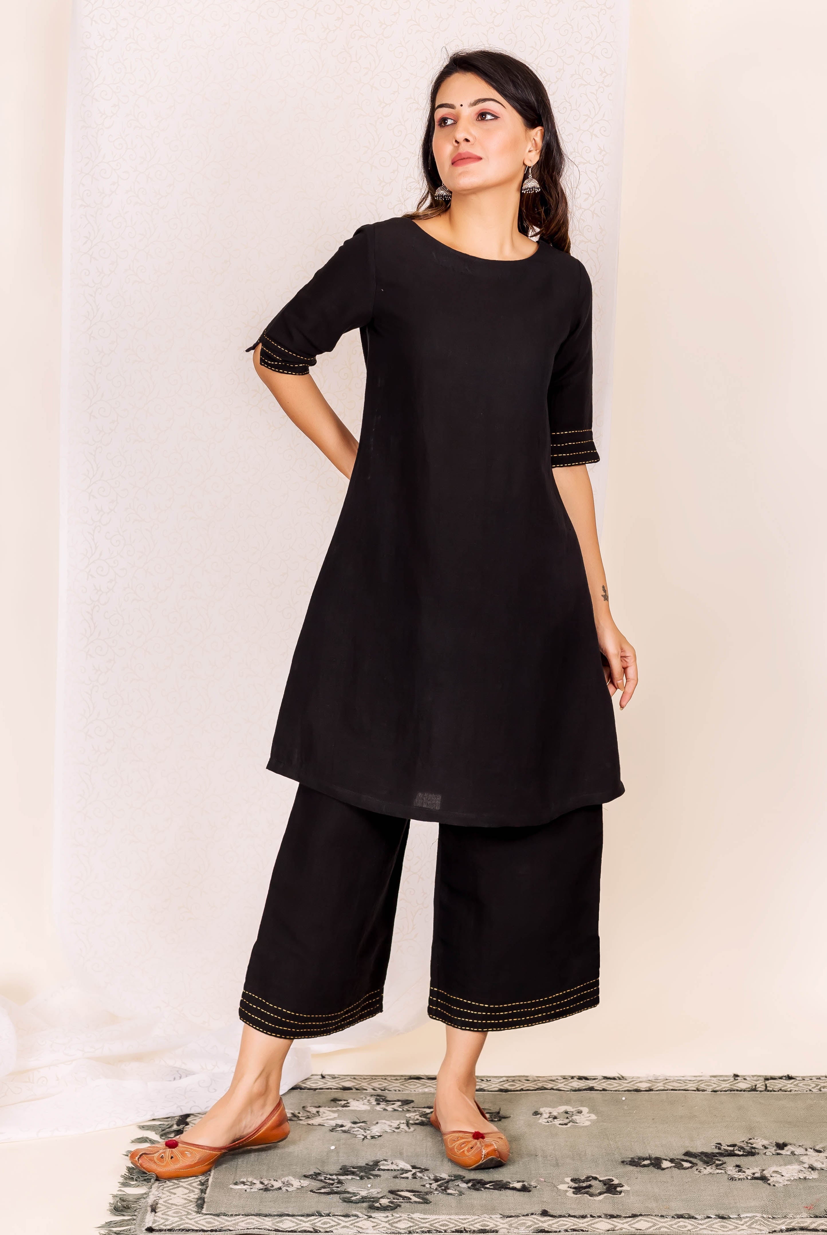 Full look, model in black linen ethnic kurta set with golden linear stitch.