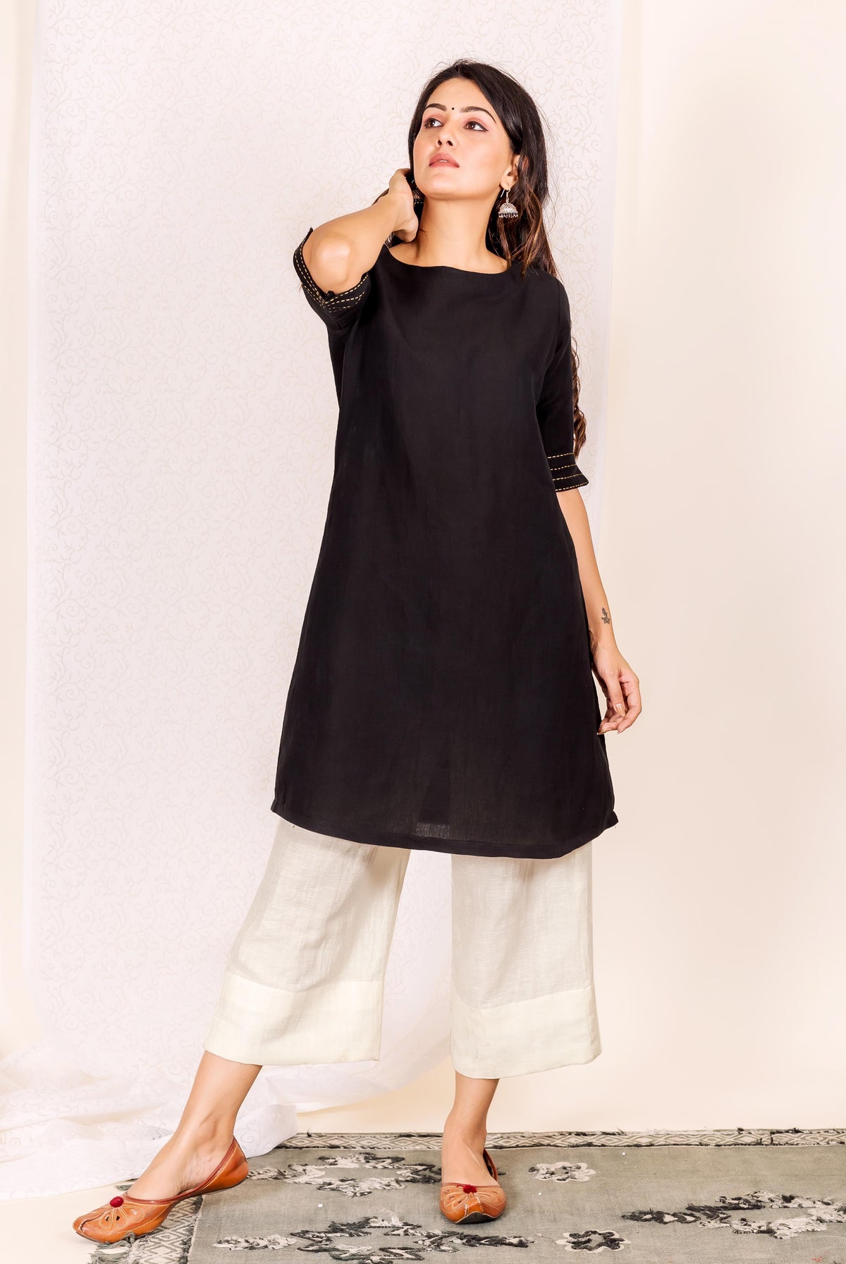 Model in black linen kurta with subtle gold hand-block print sleeves and off-white pants.