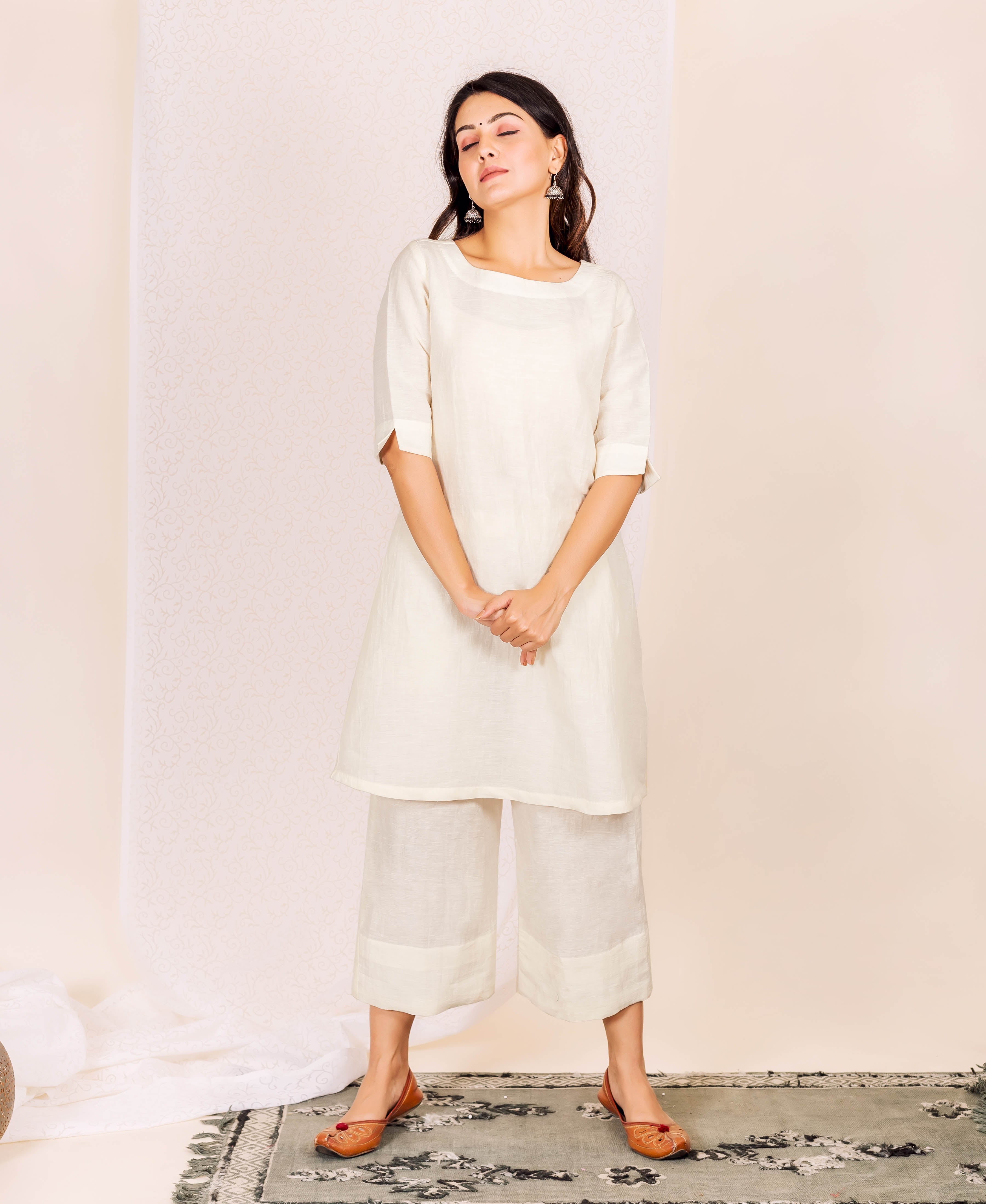 Full shot of a woman modeling a plain off-white linen boat-neck ethnic kurta set.