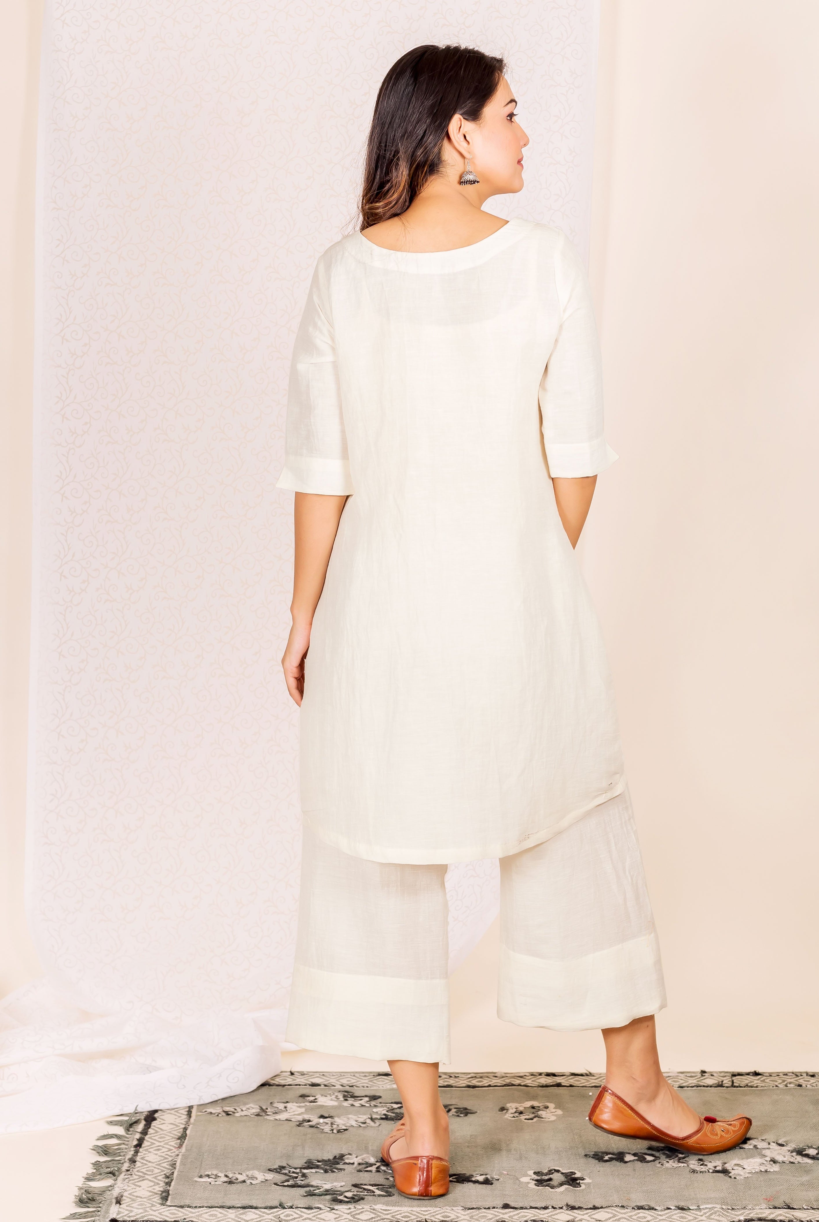 Rear view of model in an off-white linen kurta and wide-leg cropped trousers.
