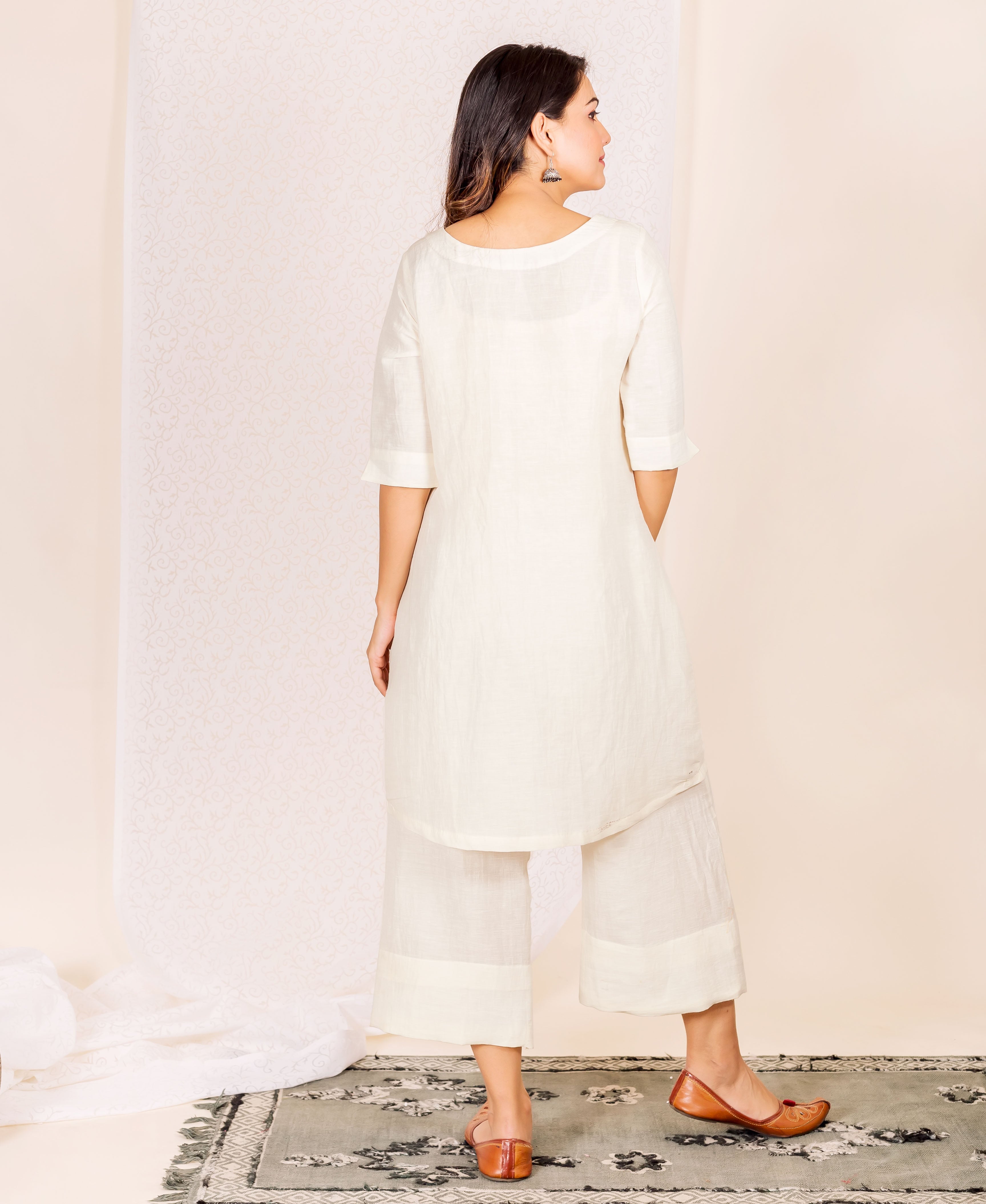 Rear view of model in an off-white linen kurta and wide-leg cropped trousers.
