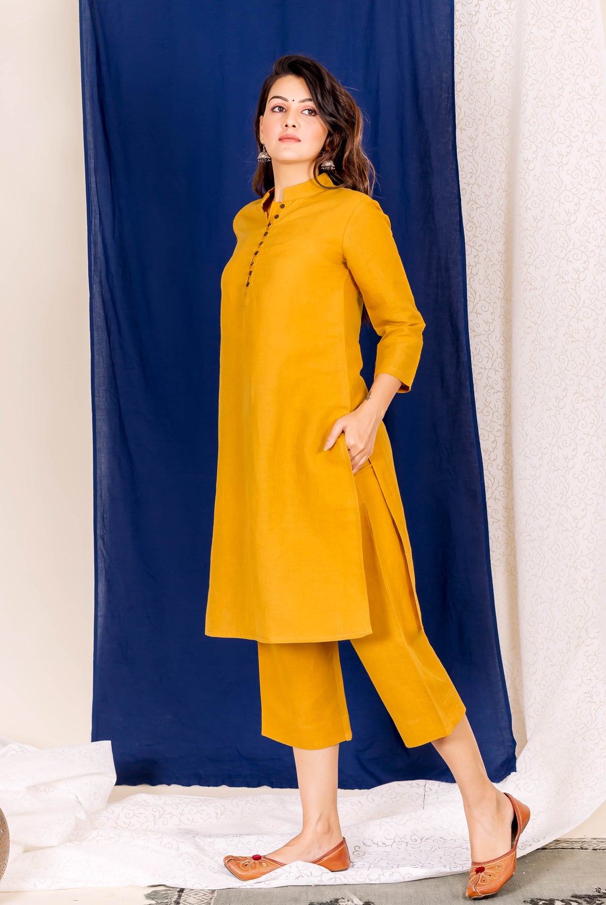 Full-length shot of a model in a plain mustard yellow linen kurta set.