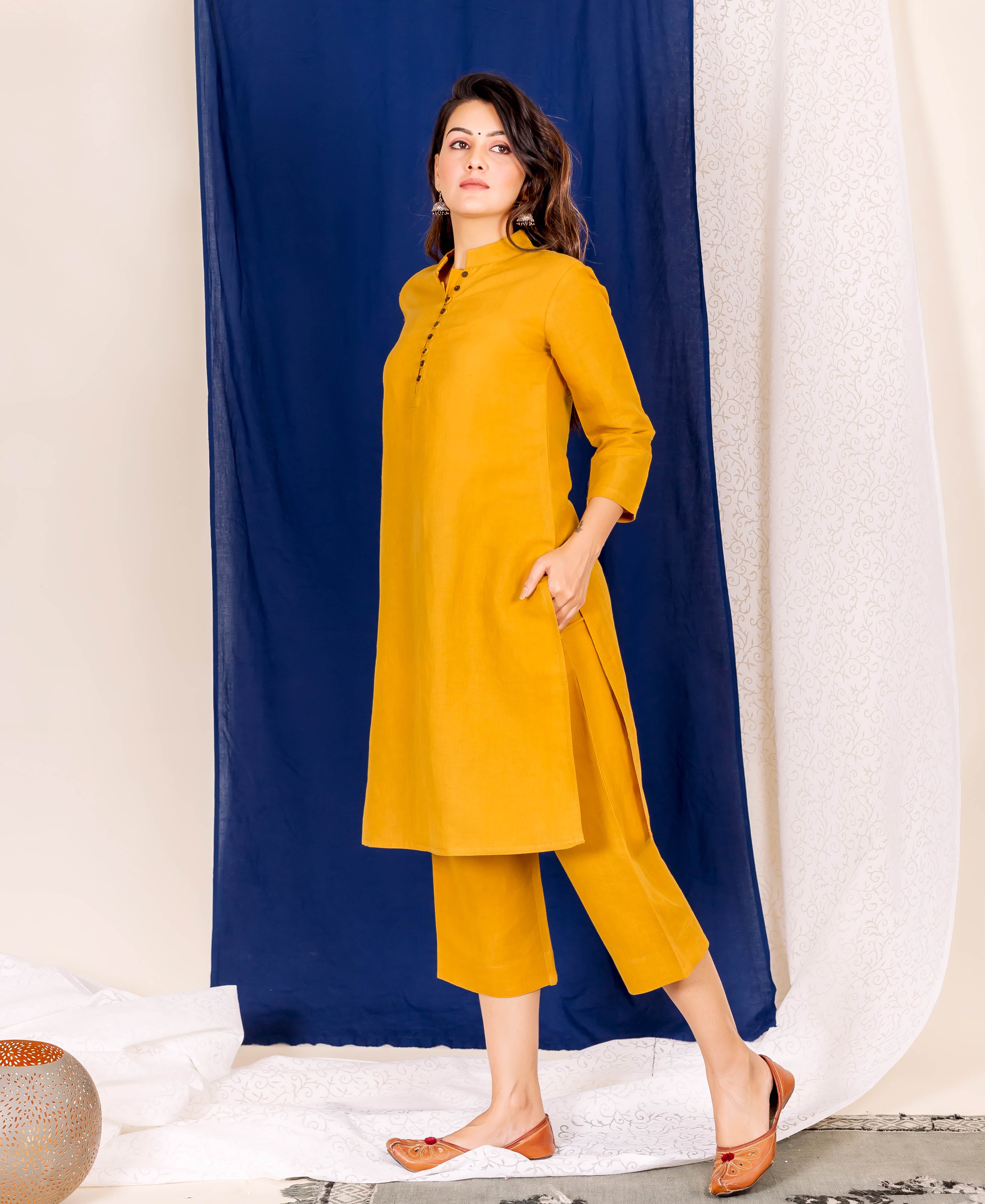 Full-length shot of a model in a plain mustard yellow linen kurta set.