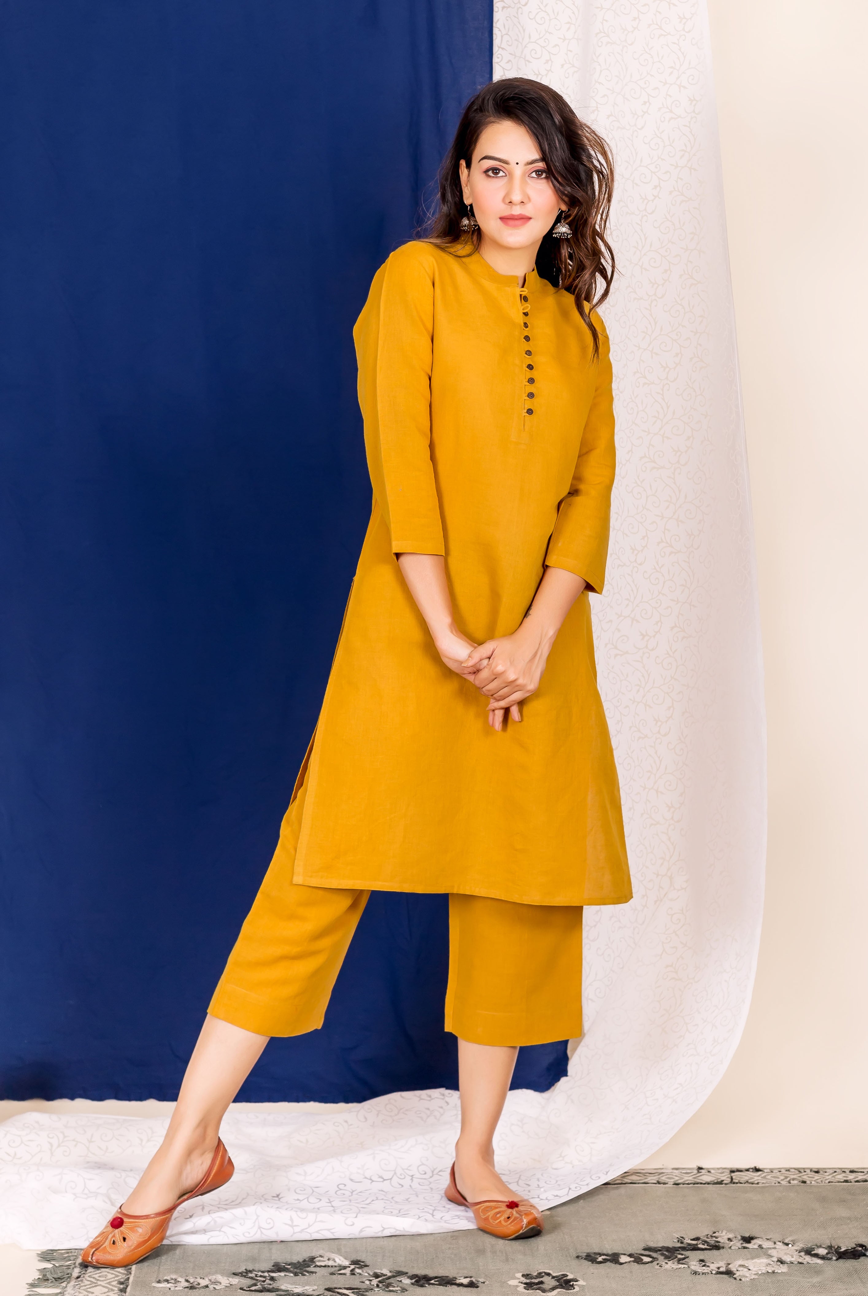 A woman wearing a mustard linen kurta with black buttons and a matching pair of pants.