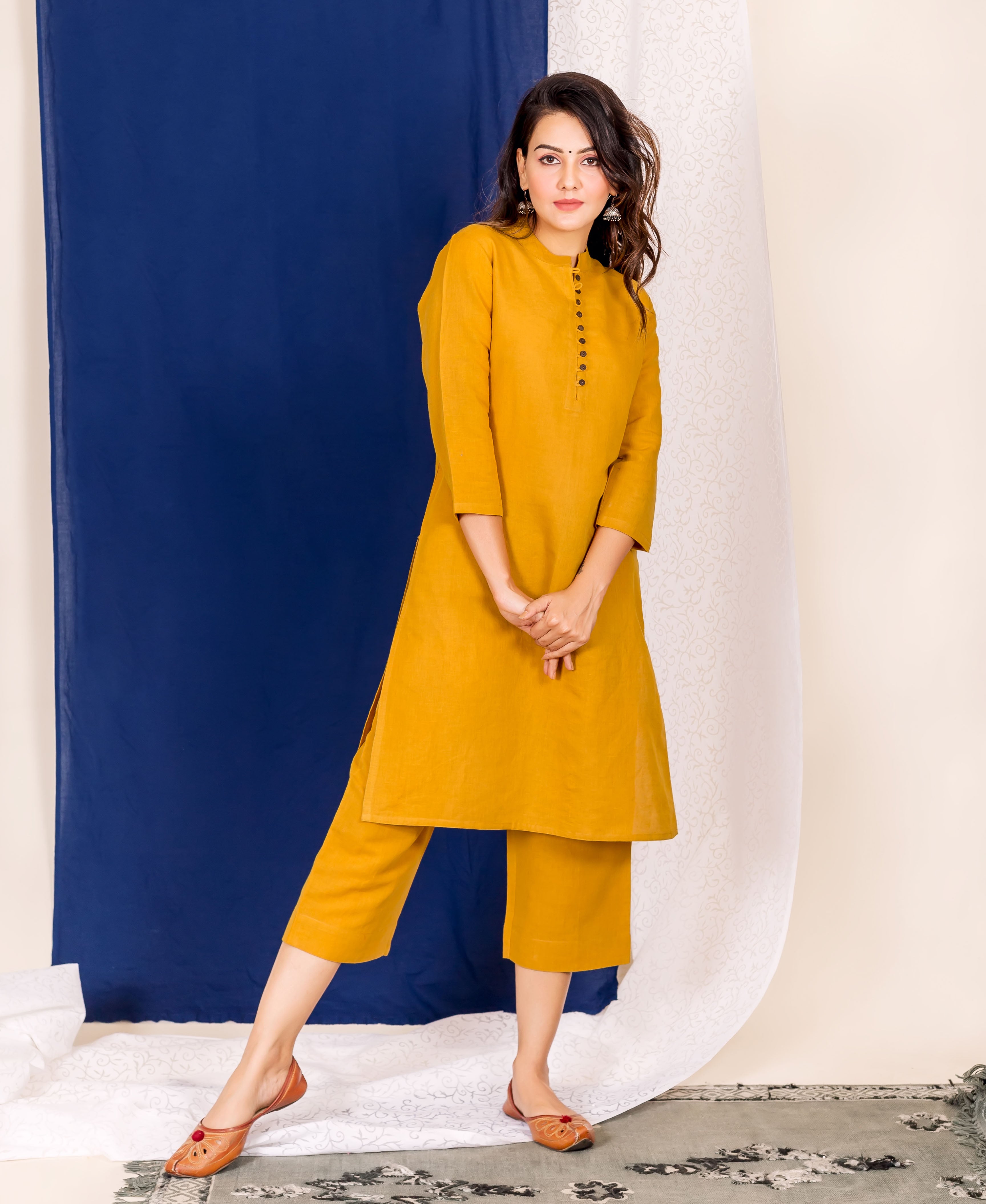 A woman wearing a mustard linen kurta with black buttons and a matching pair of pants.