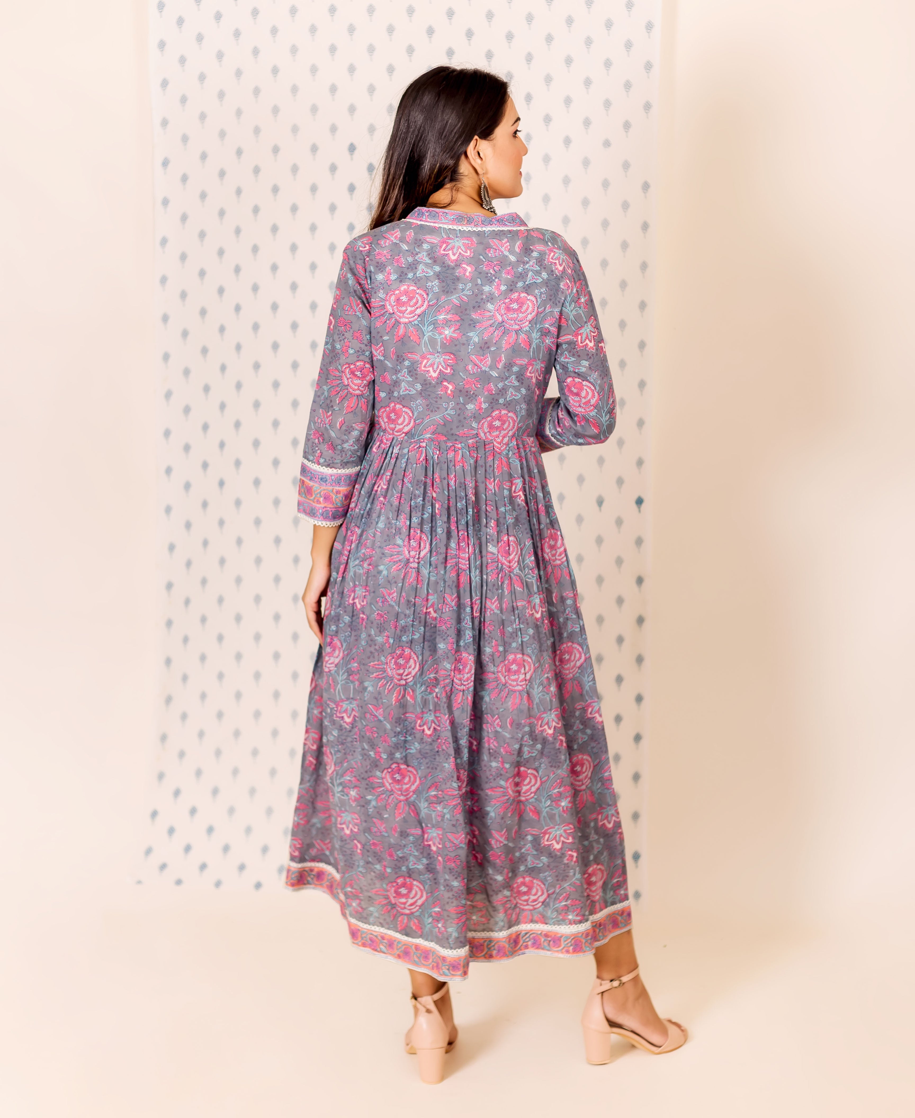 A model wearing a grey and pink hand block printed dress with an inner lining.
