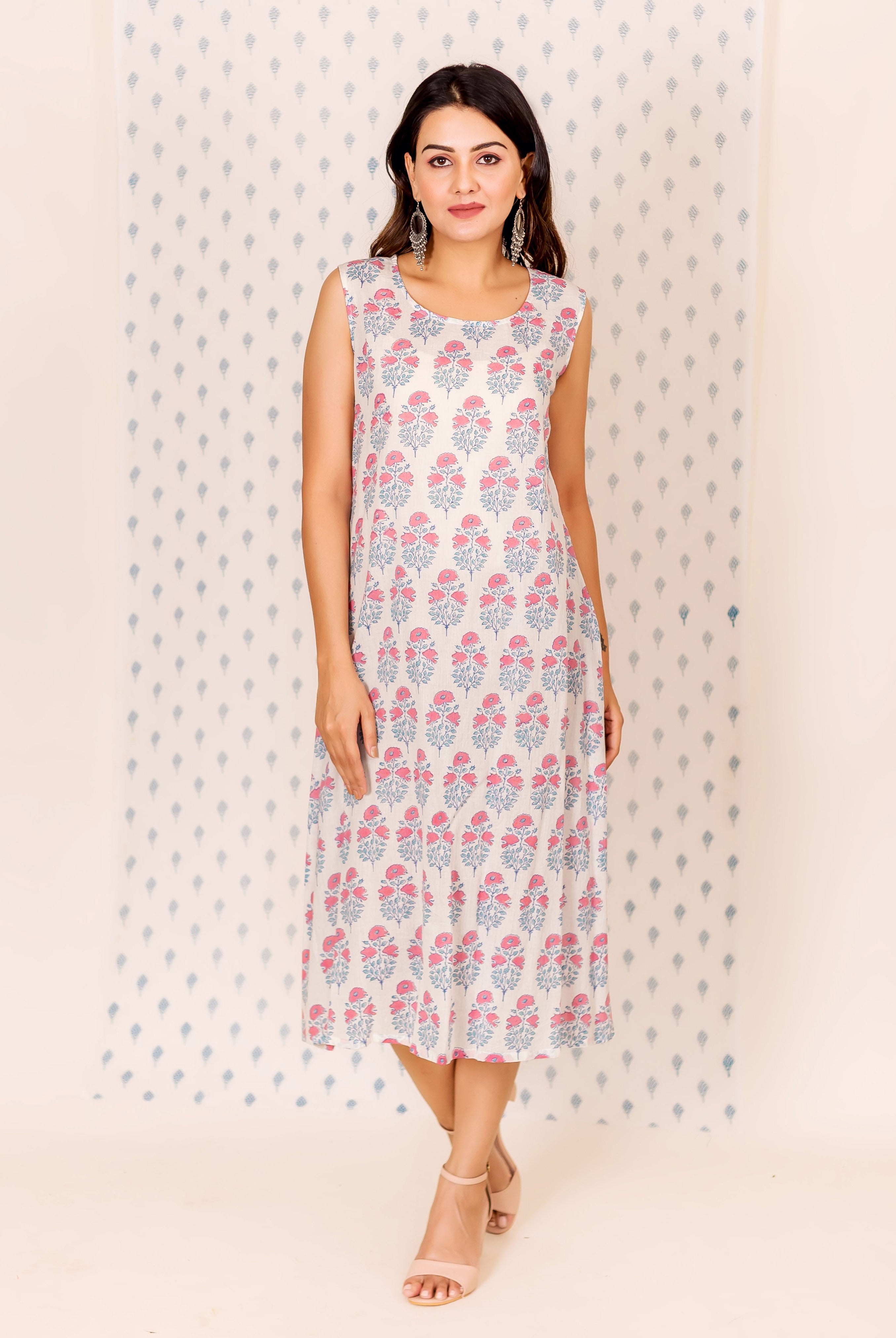 Front view of model wearing a sleeveless cream dress with pink and bluish-grey floral block print.