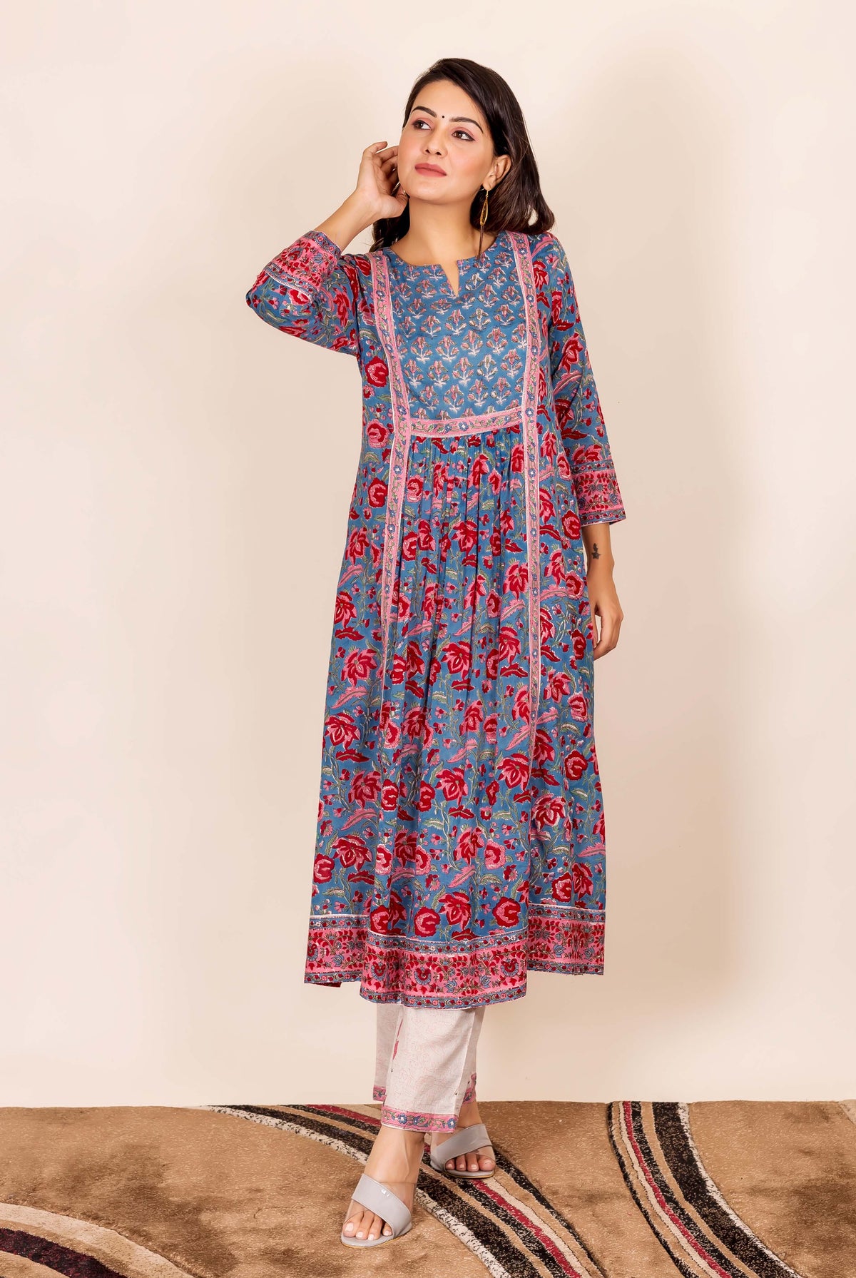 Model wearing a blue and red hand block printed kurta with white pants, standing.