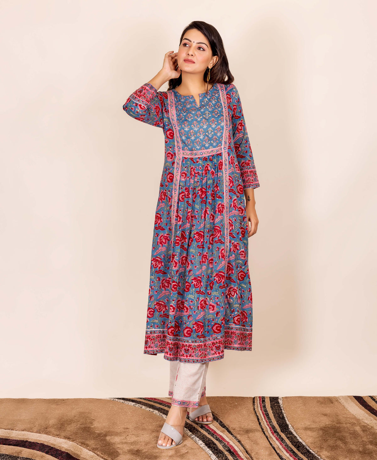 Model wearing a blue and red hand block printed kurta with white pants, standing.