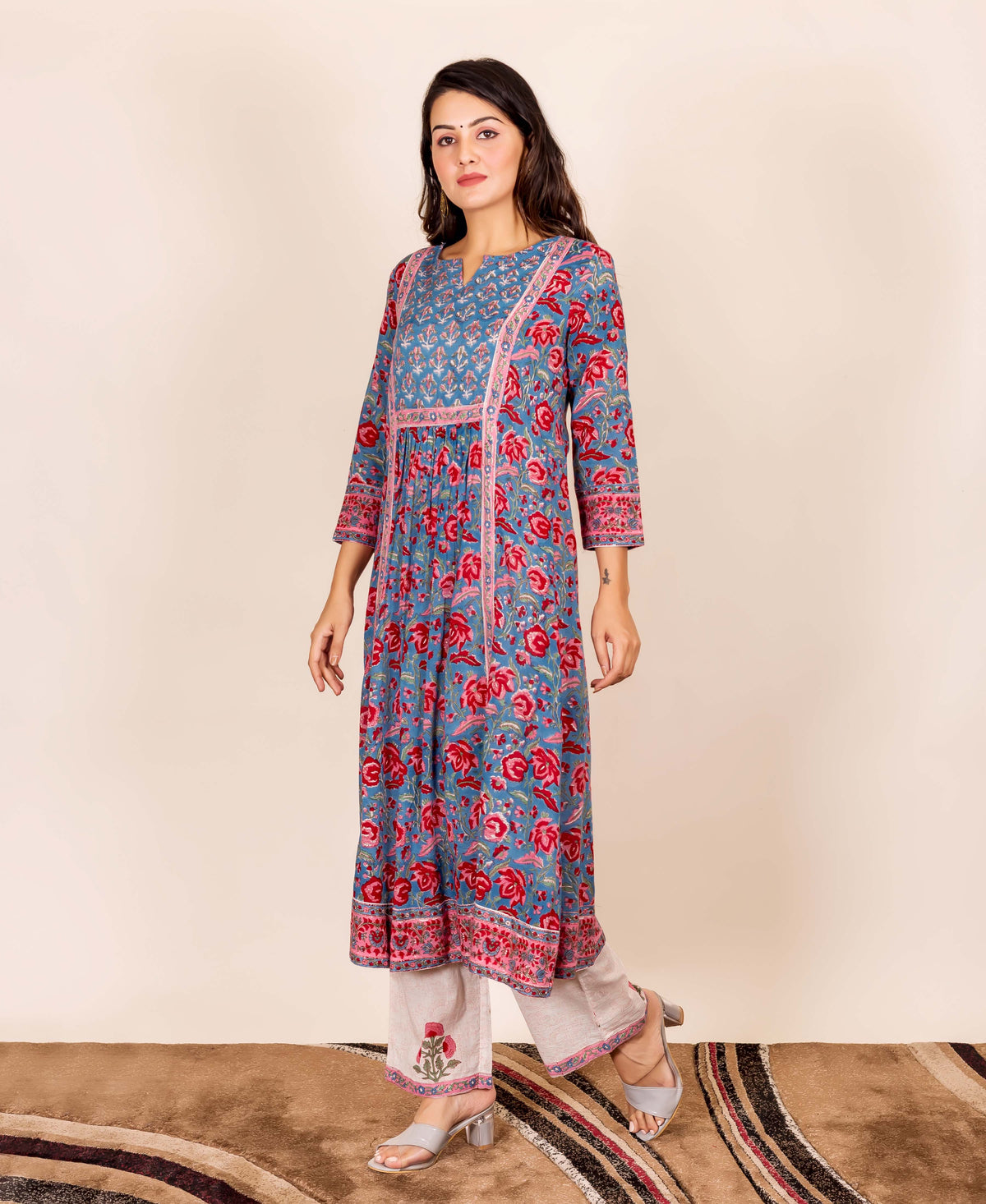 Model wearing a blue and red floral hand block printed kurta with beige pants.