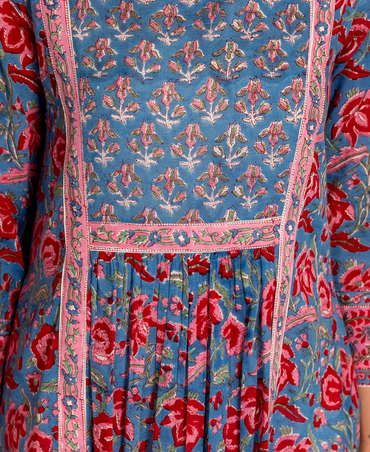 Close-up of blue and red hand block printed kurta, featuring varied floral patterns and pink trim.