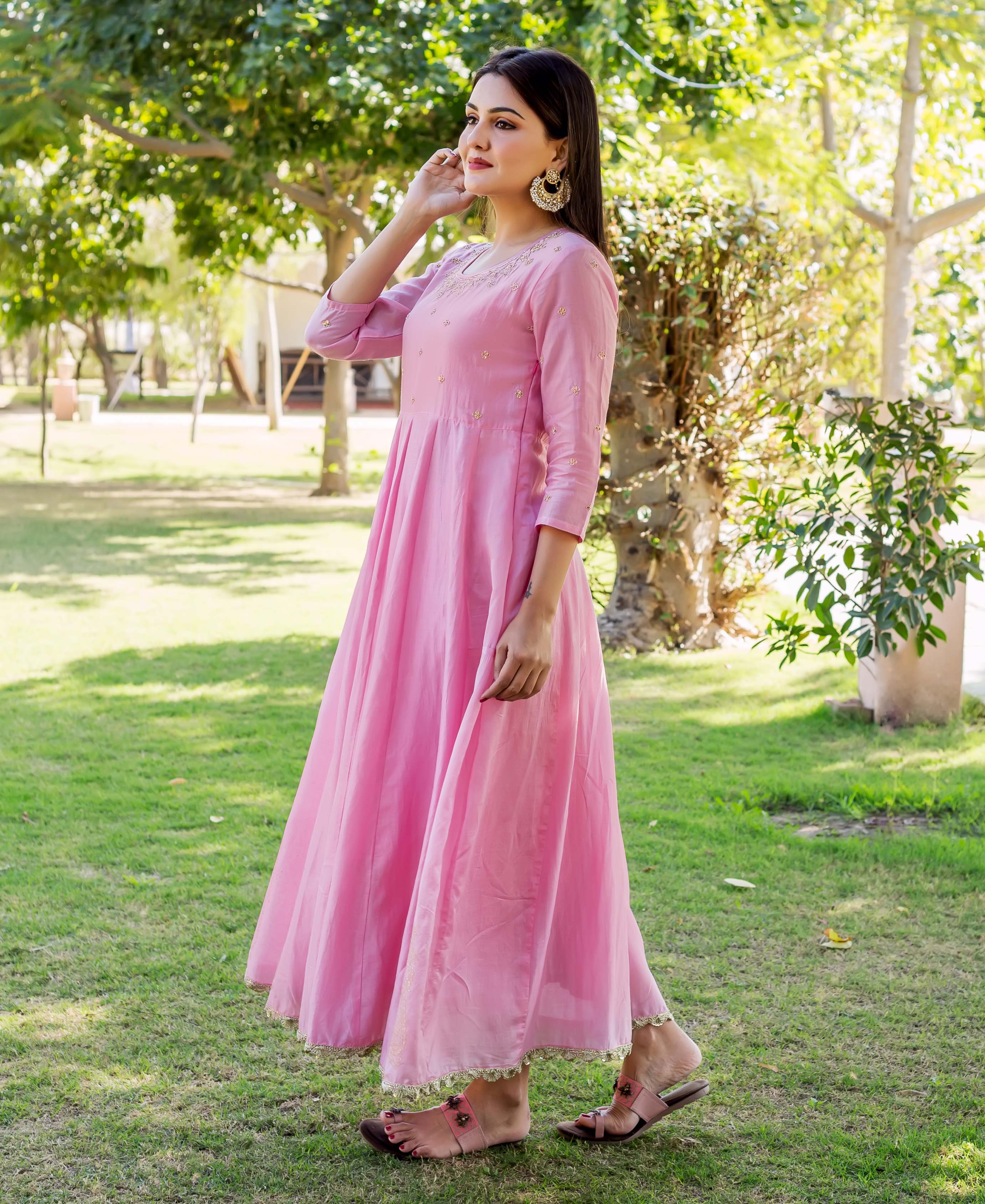 Side view of a model in a blush pink embroidered flowing ethnic dress.