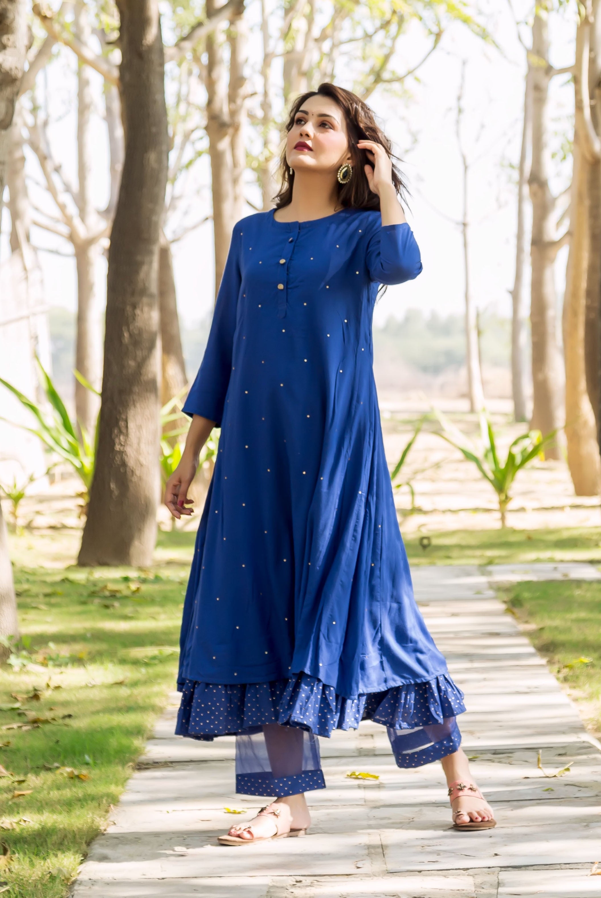 Full shot of model in azure blue embroidered kurta, layered with polka dot ruffled pants.