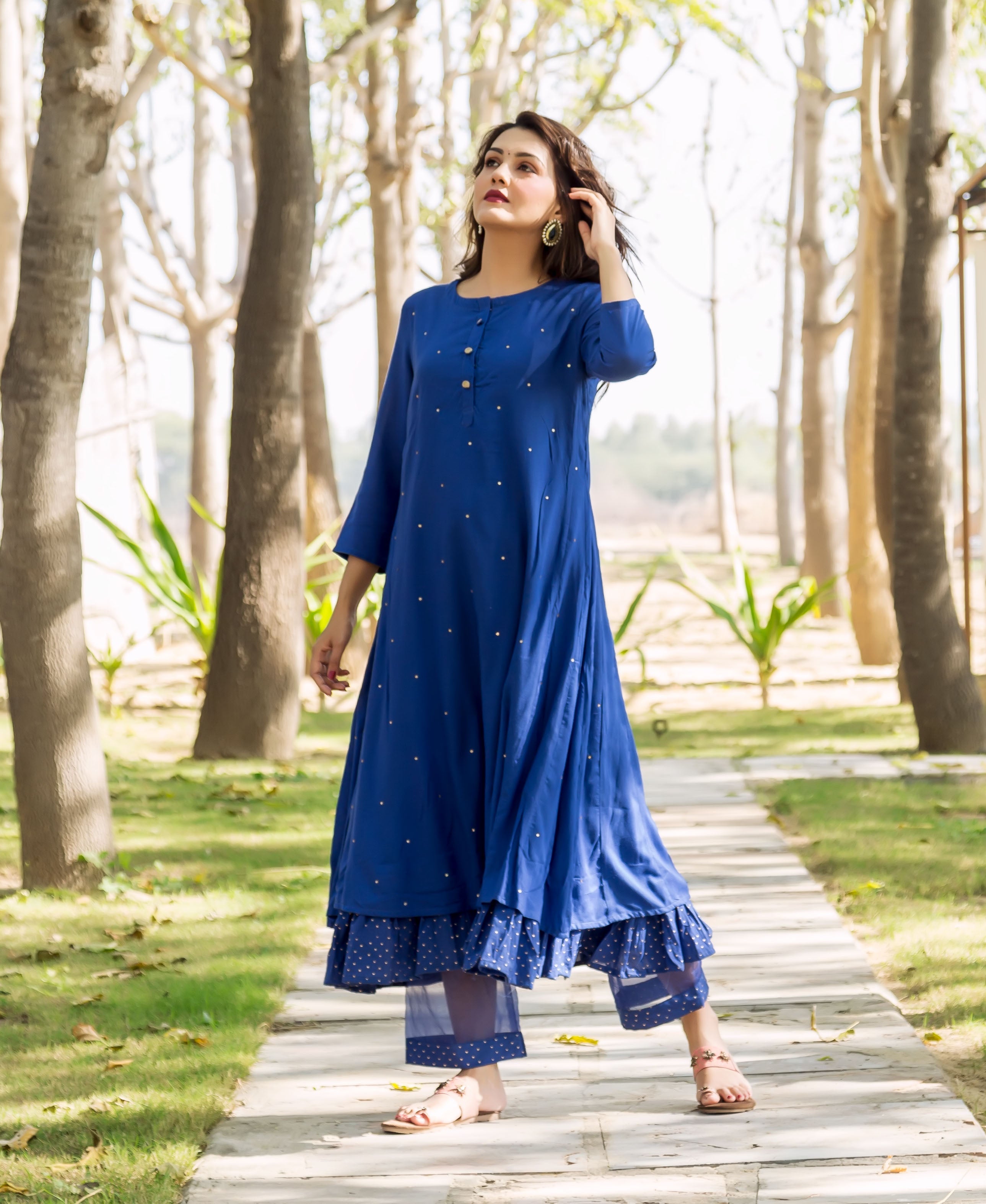 Full shot of model in azure blue embroidered kurta, layered with polka dot ruffled pants.