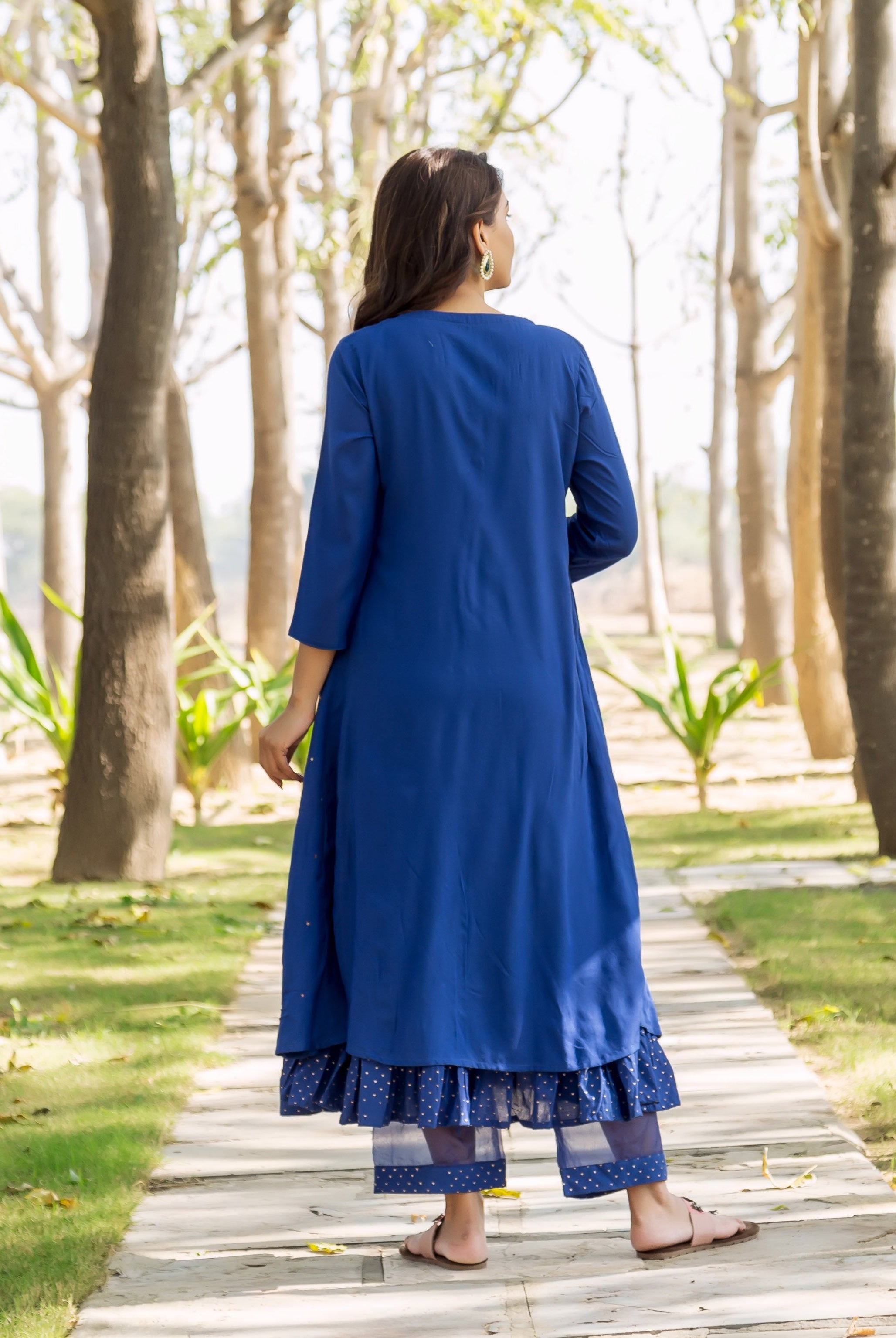 Back view of model in azure blue embroidered kurta over layered polka dot pants.
