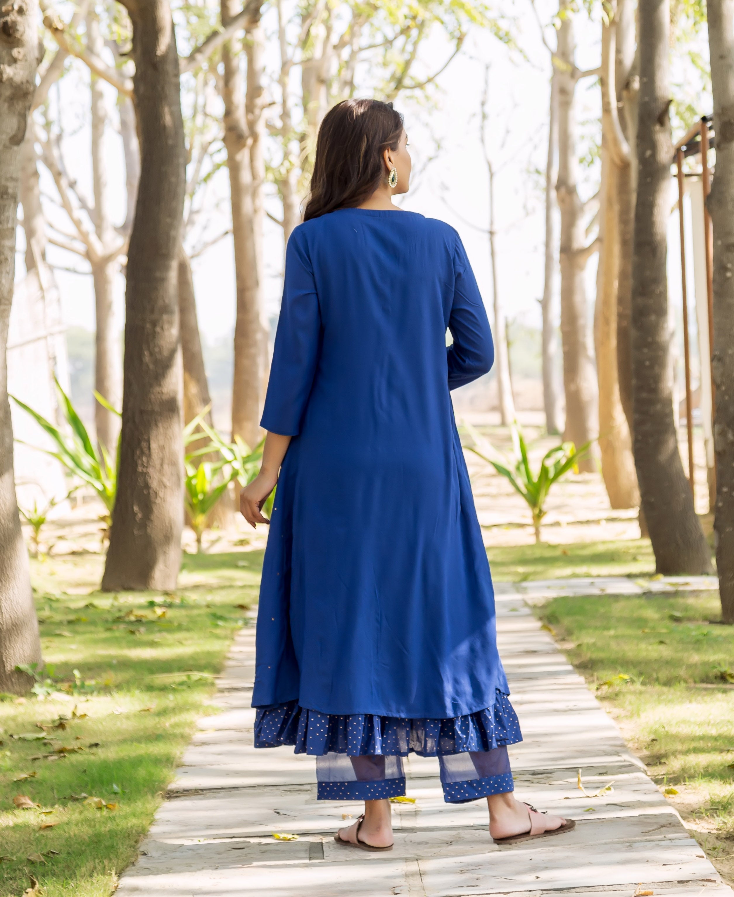 Back view of model in azure blue embroidered kurta over layered polka dot pants.