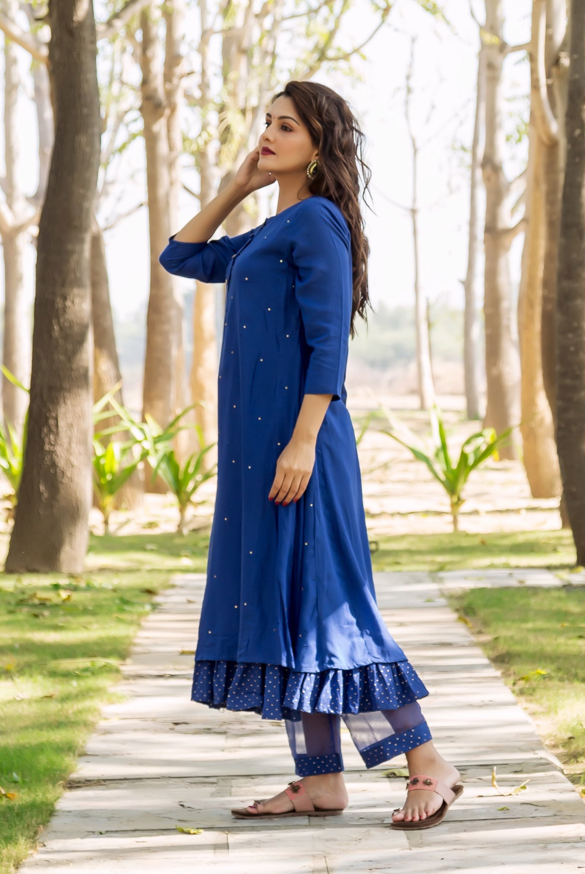Side view: model in azure blue embroidered kurta and layered polka dot pants.