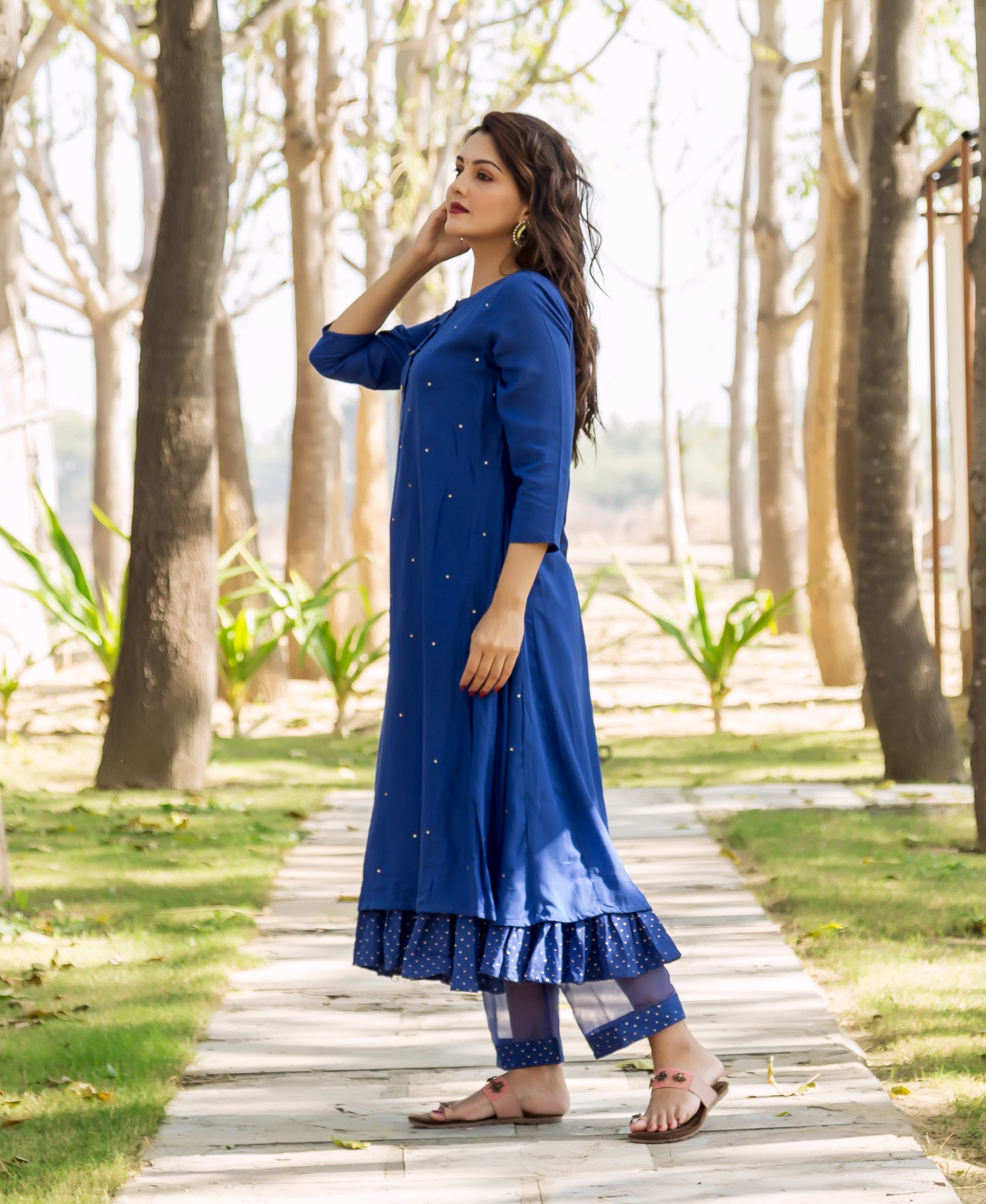 Side view: model in azure blue embroidered kurta and layered polka dot pants.