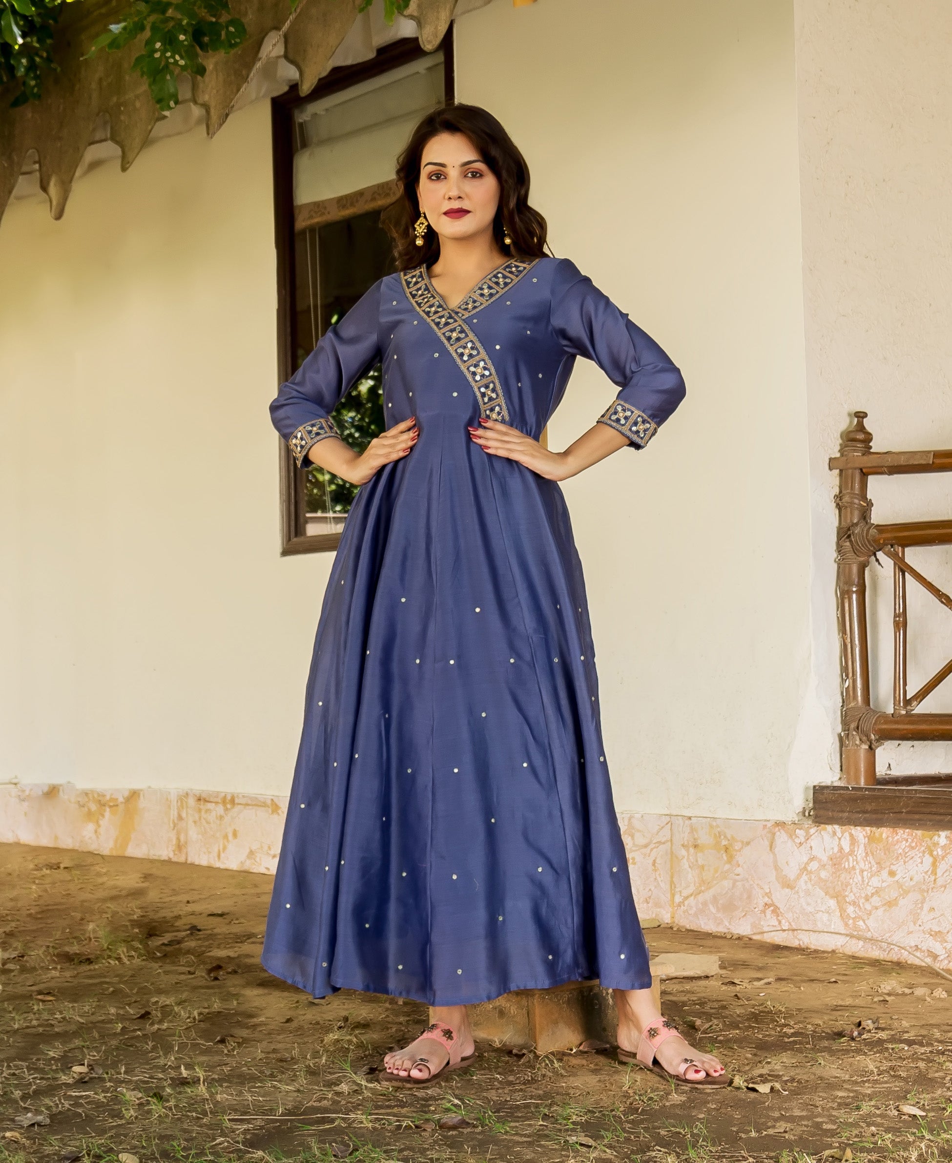 Model in a flowing steel blue hand-embroidered Angrakha dress with gold accents.