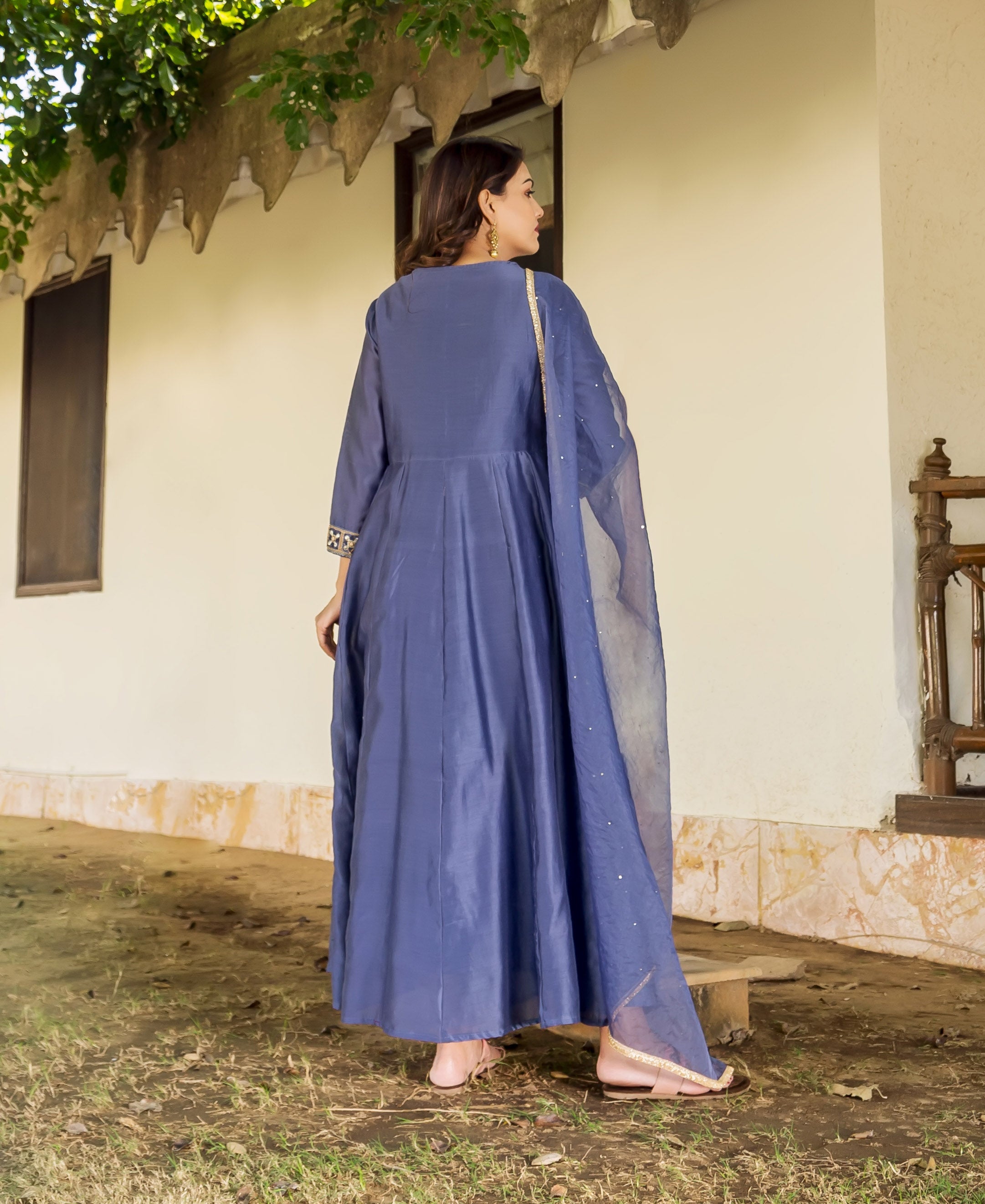Back view of model in flowing steel blue chanderi dress with embroidered cuffs and dupatta.