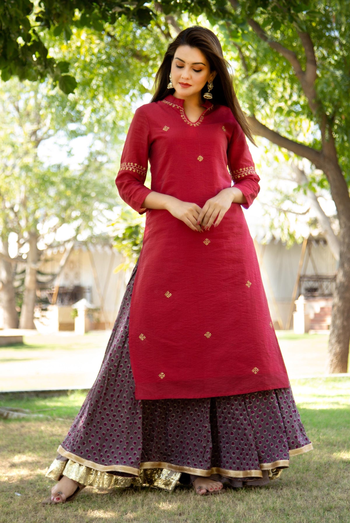 Model in a maroon embroidered kurta paired with a patterned grey skirt with gold border.