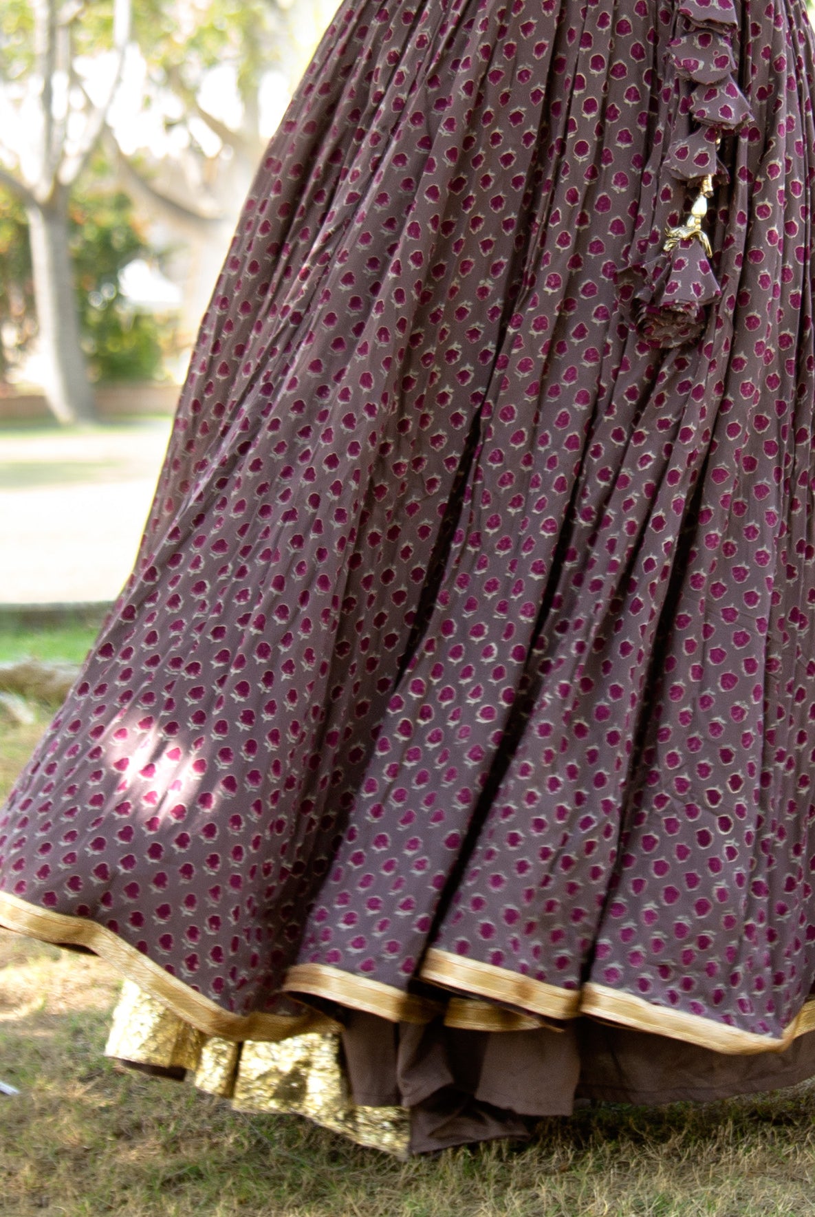 Flowing cedar brown skirt with deep purple block print dots, gold gota border, and tassels.