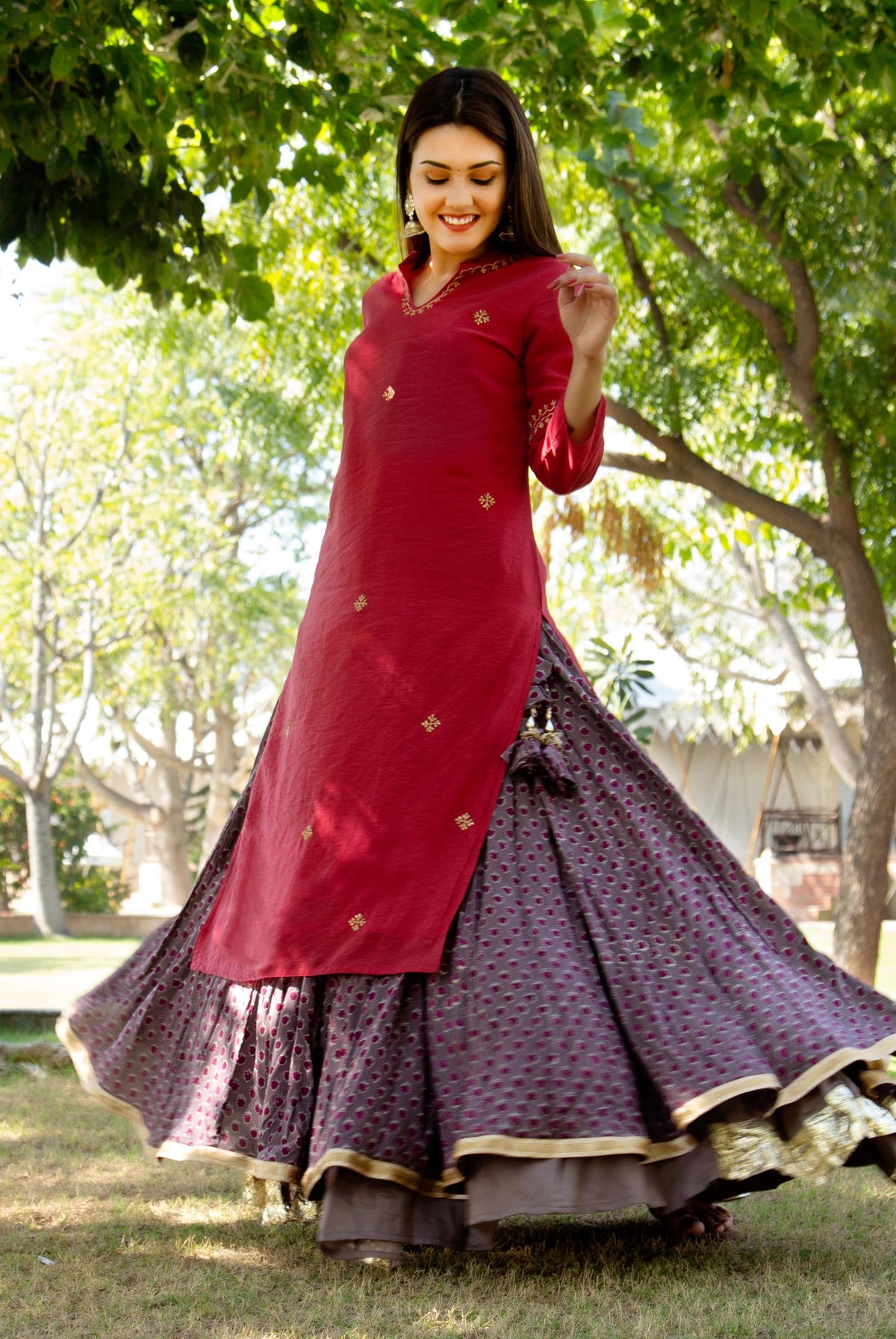 Woman in a red kurta with gold details and a flowing hand-block-printed cedar brown skirt.