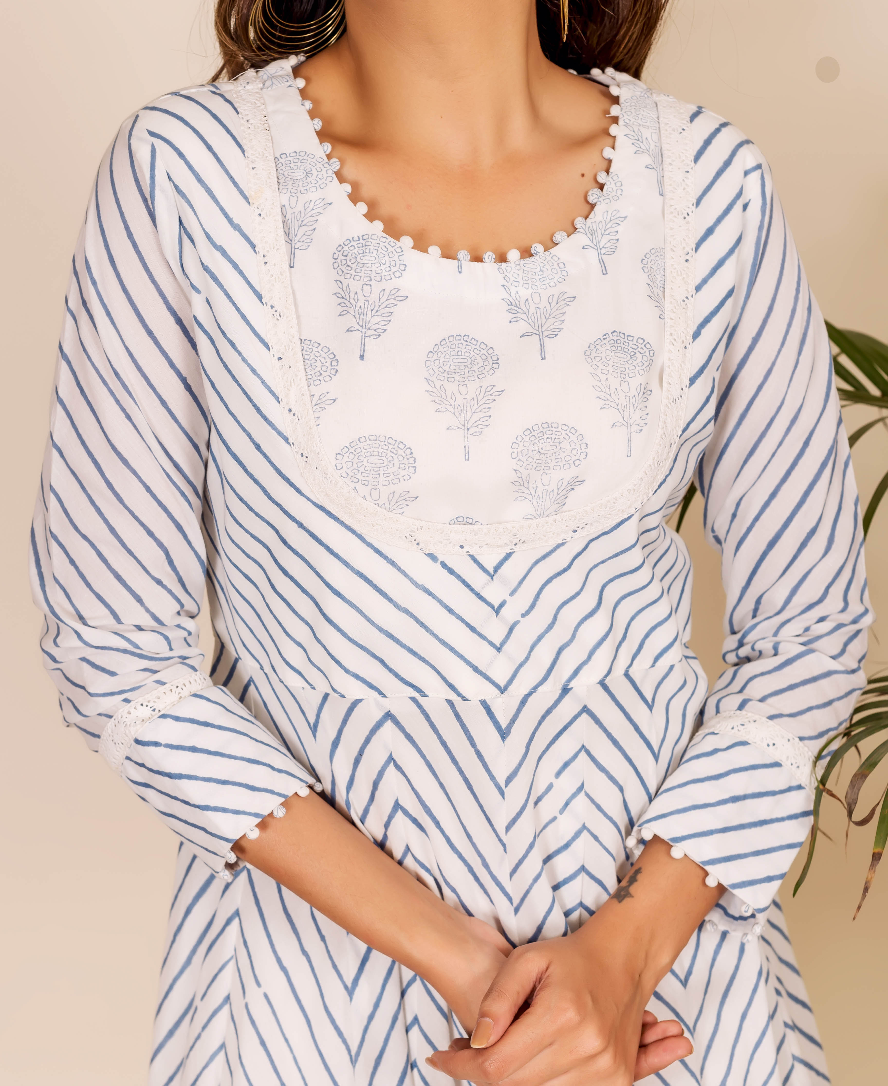 Front view of a woman in a white and blue hand-block-printed zig-zag dress with lace trim.