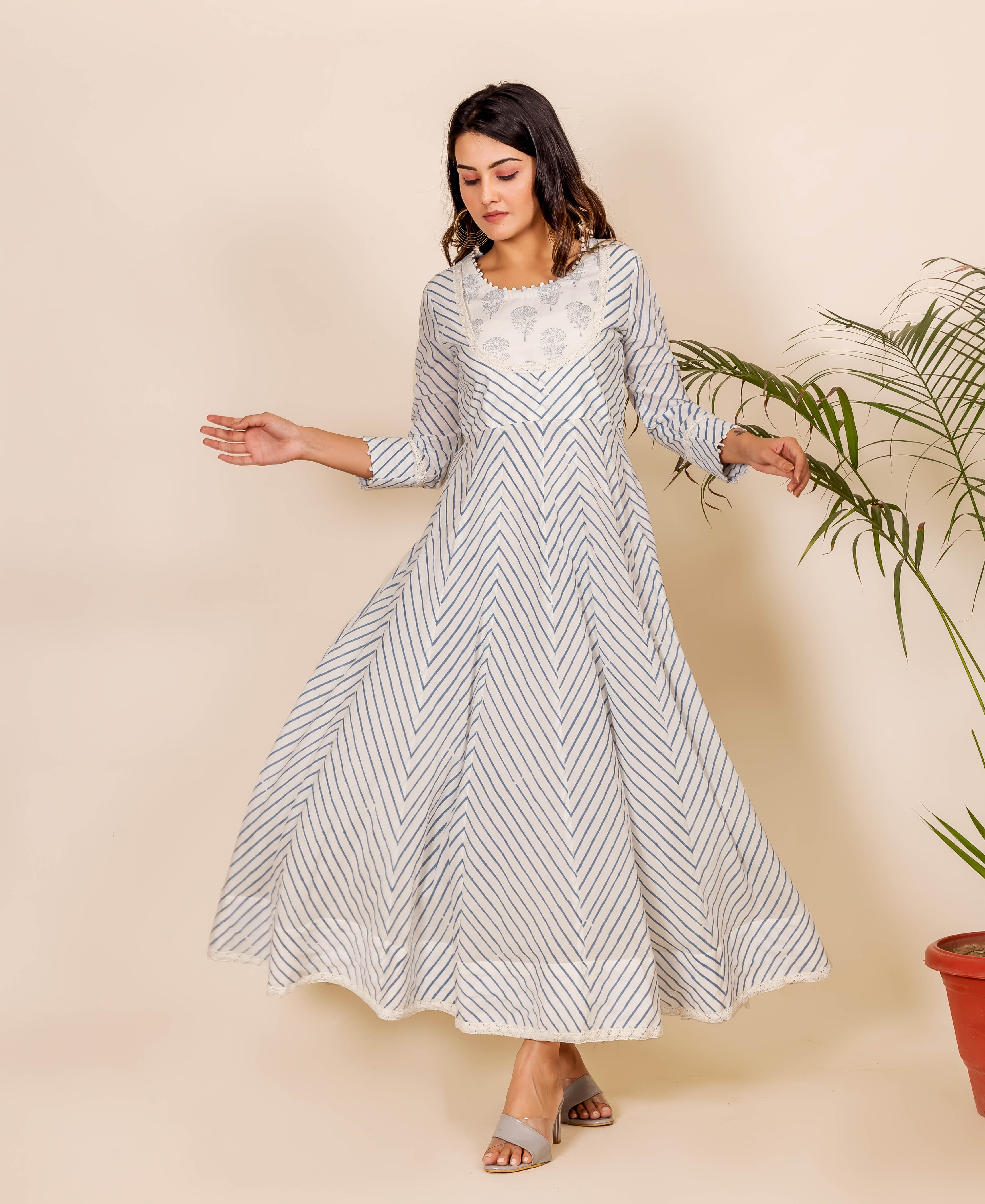 Full-length shot of model wearing a white Anarkali dress with blue zig-zag block prints.
