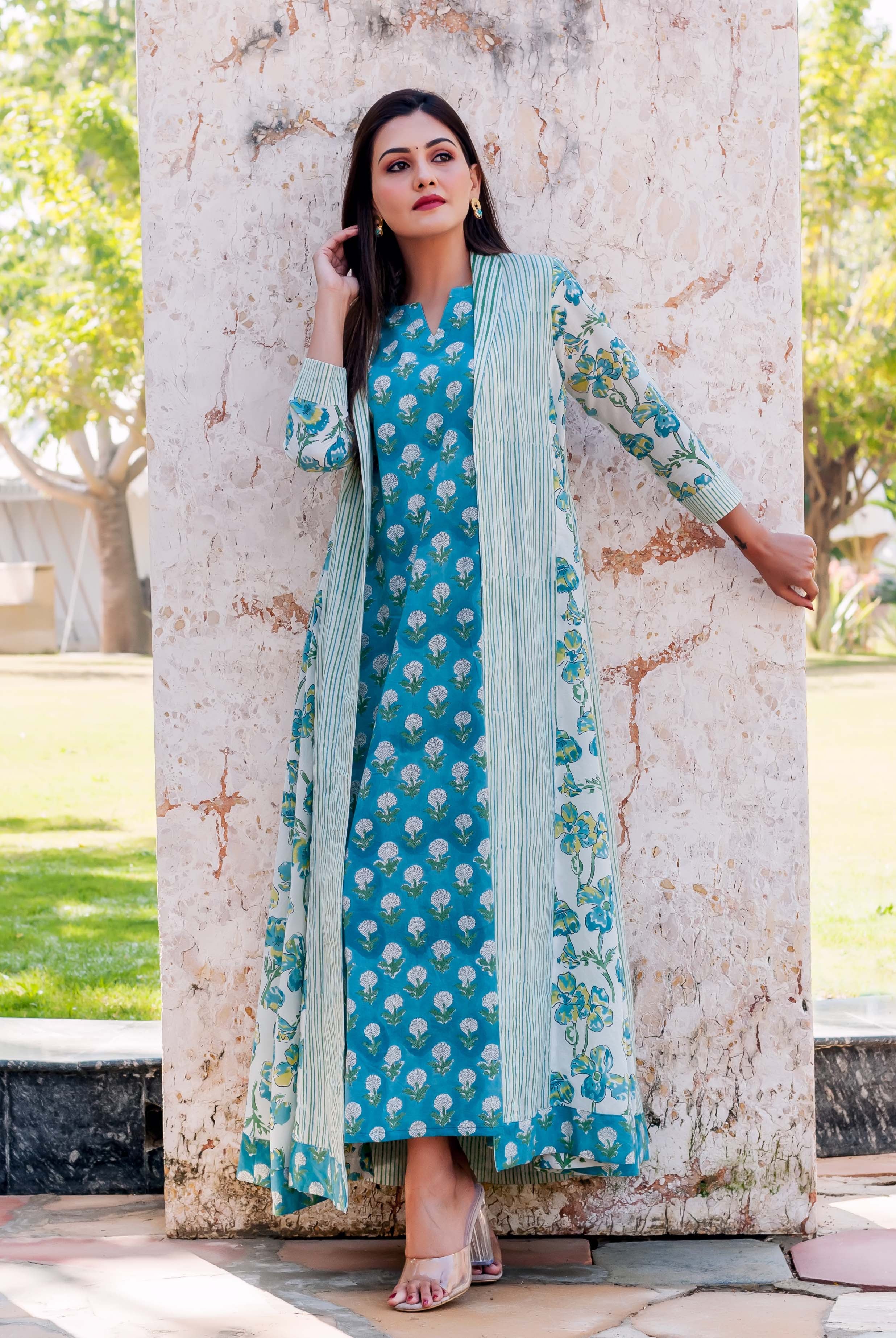 Woman wearing a vibrant teal floral dress with a long striped and floral print jacket.