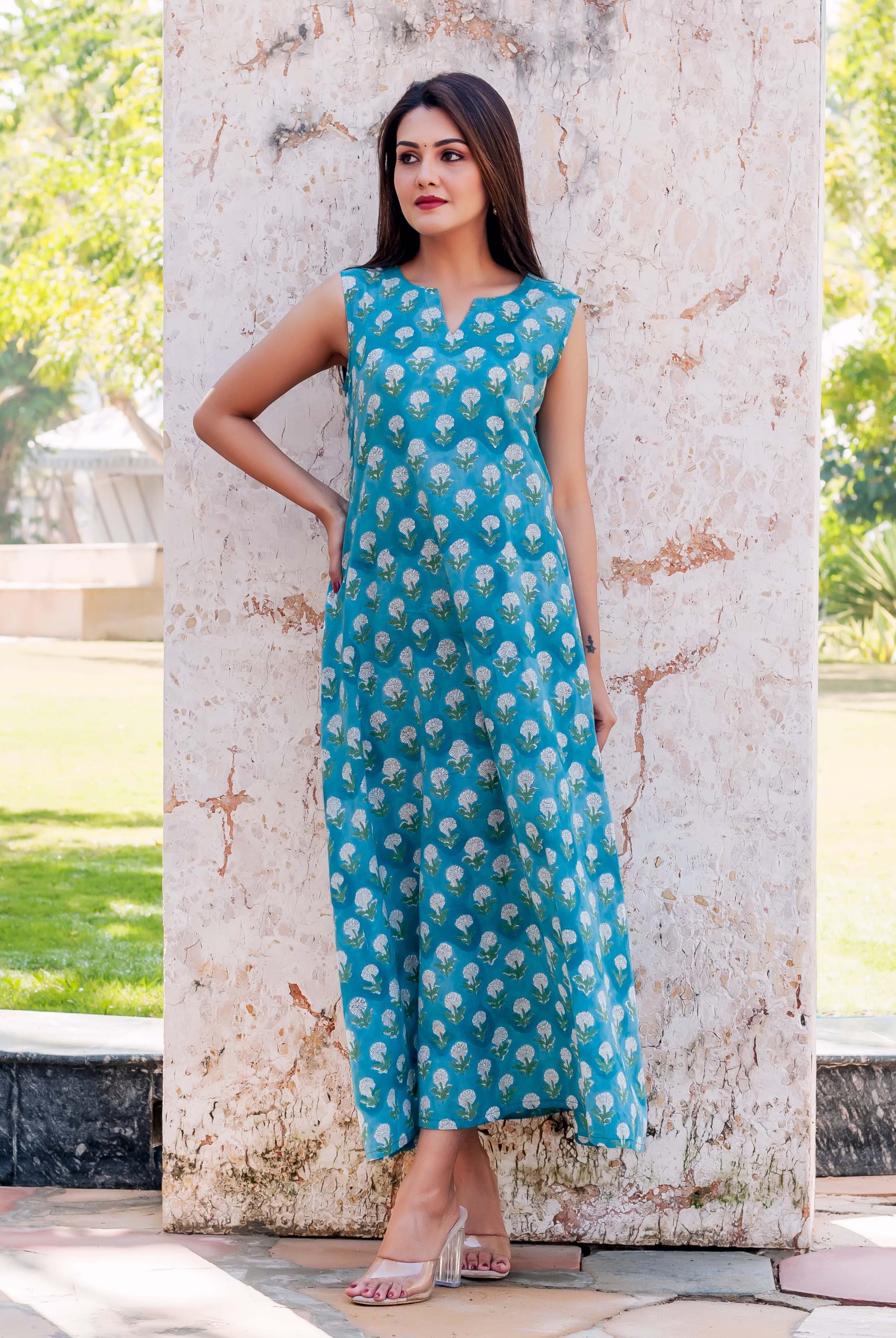 Model posed in blue sleeveless V-neck long dress with all-over white floral print, full look.