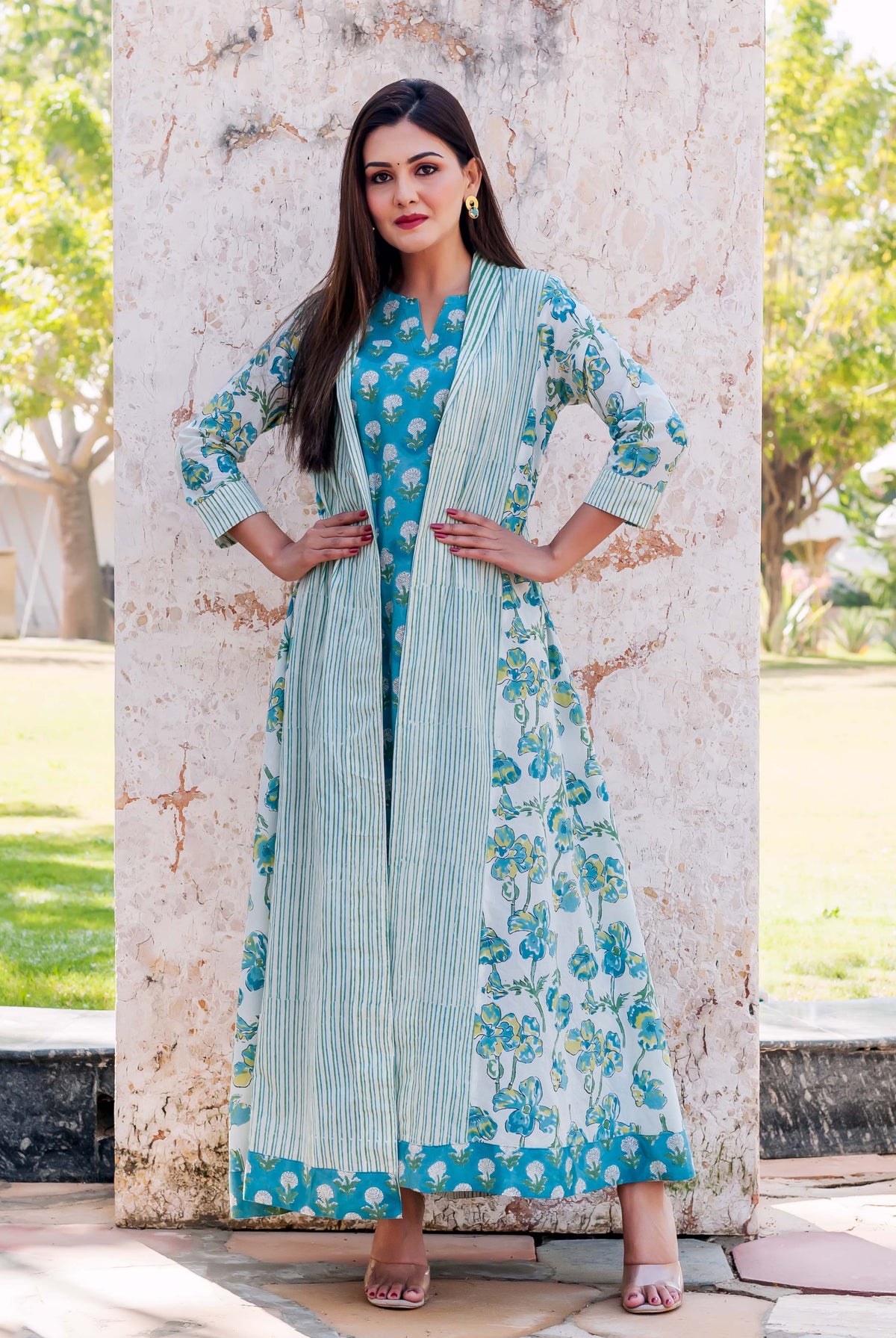 A woman in a blue and white floral dress with a striped jacket.