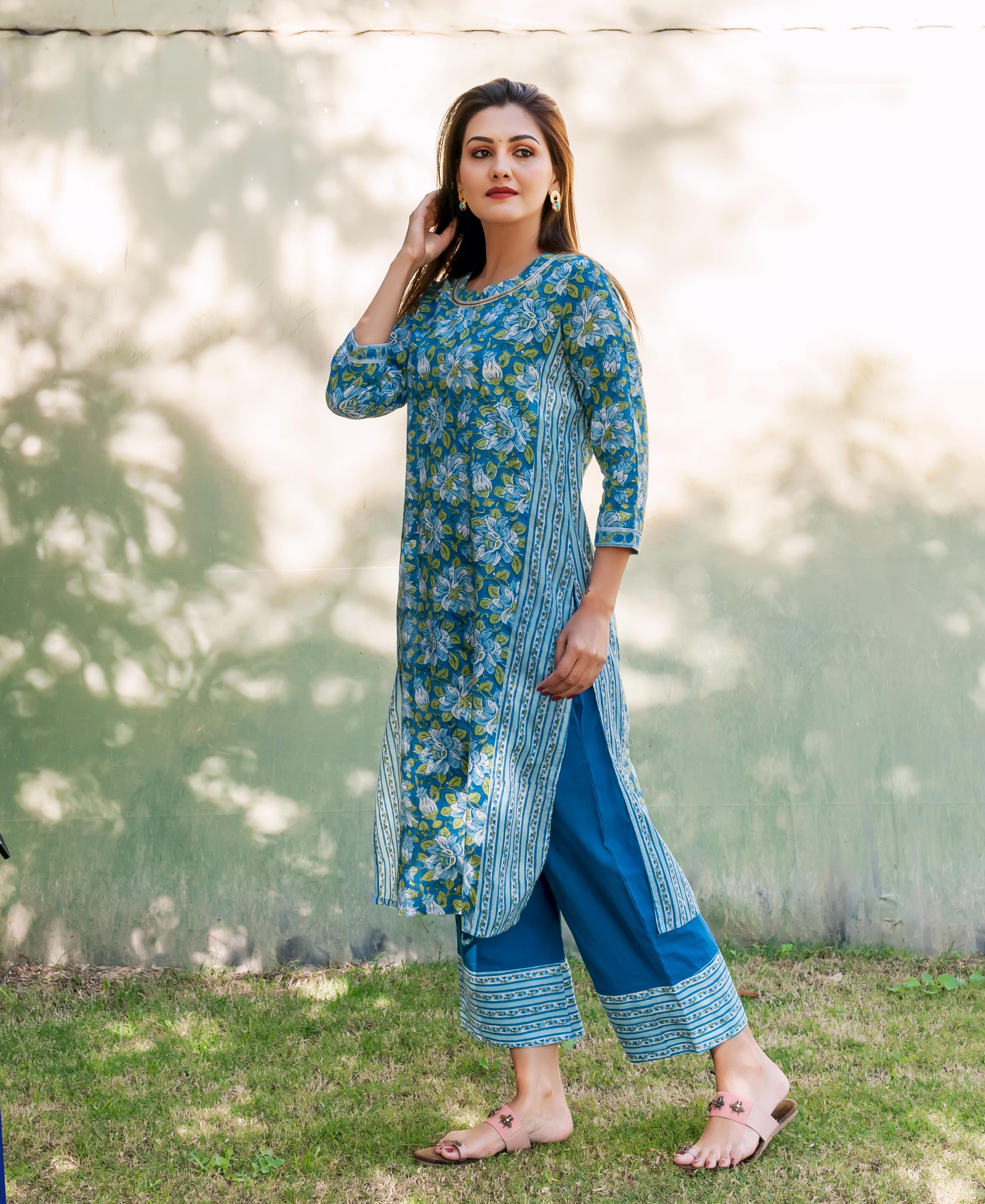 Woman wearing a blue floral hand block printed kurta and matching striped palazzo pants.