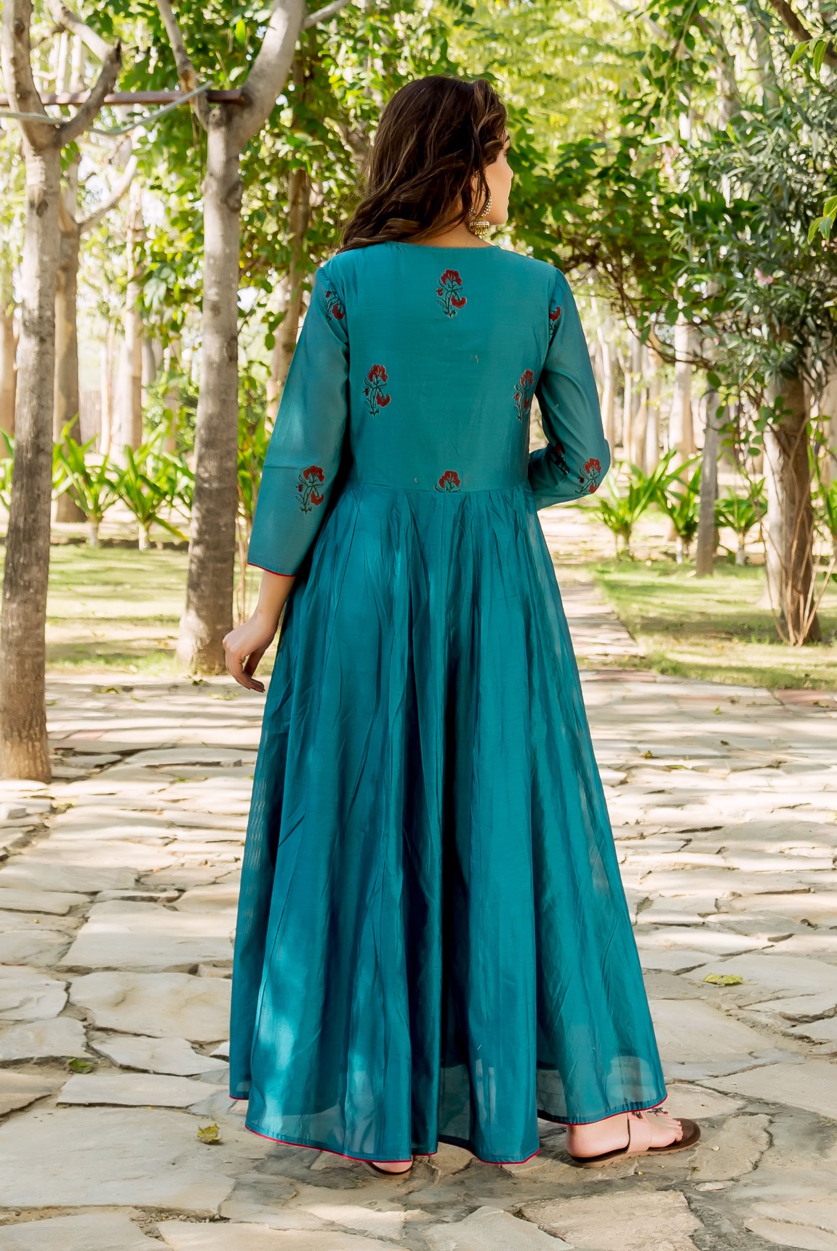 Back view of model in flowing teal kurta with red floral hand-block prints.