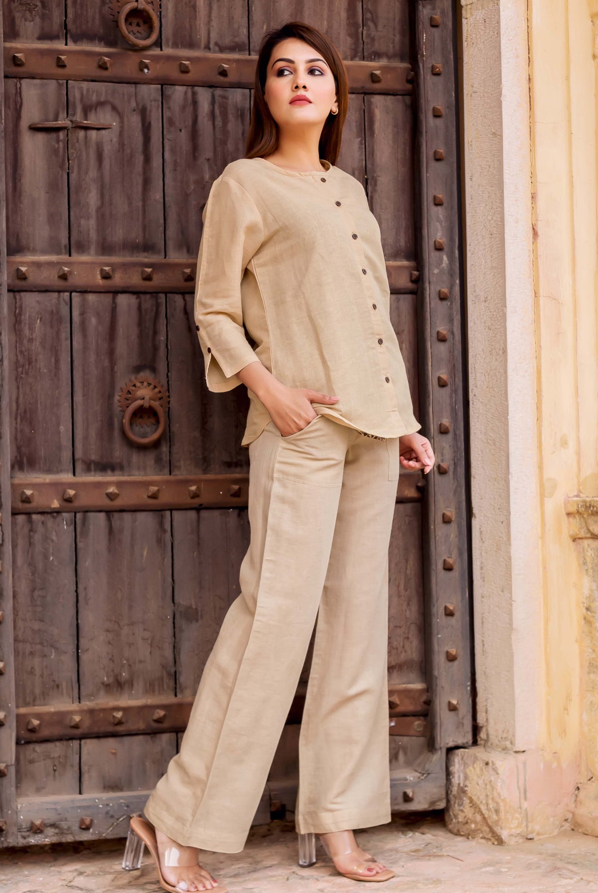 Model in a beige linen coordinated set, a buttoned top and wide-leg trousers.