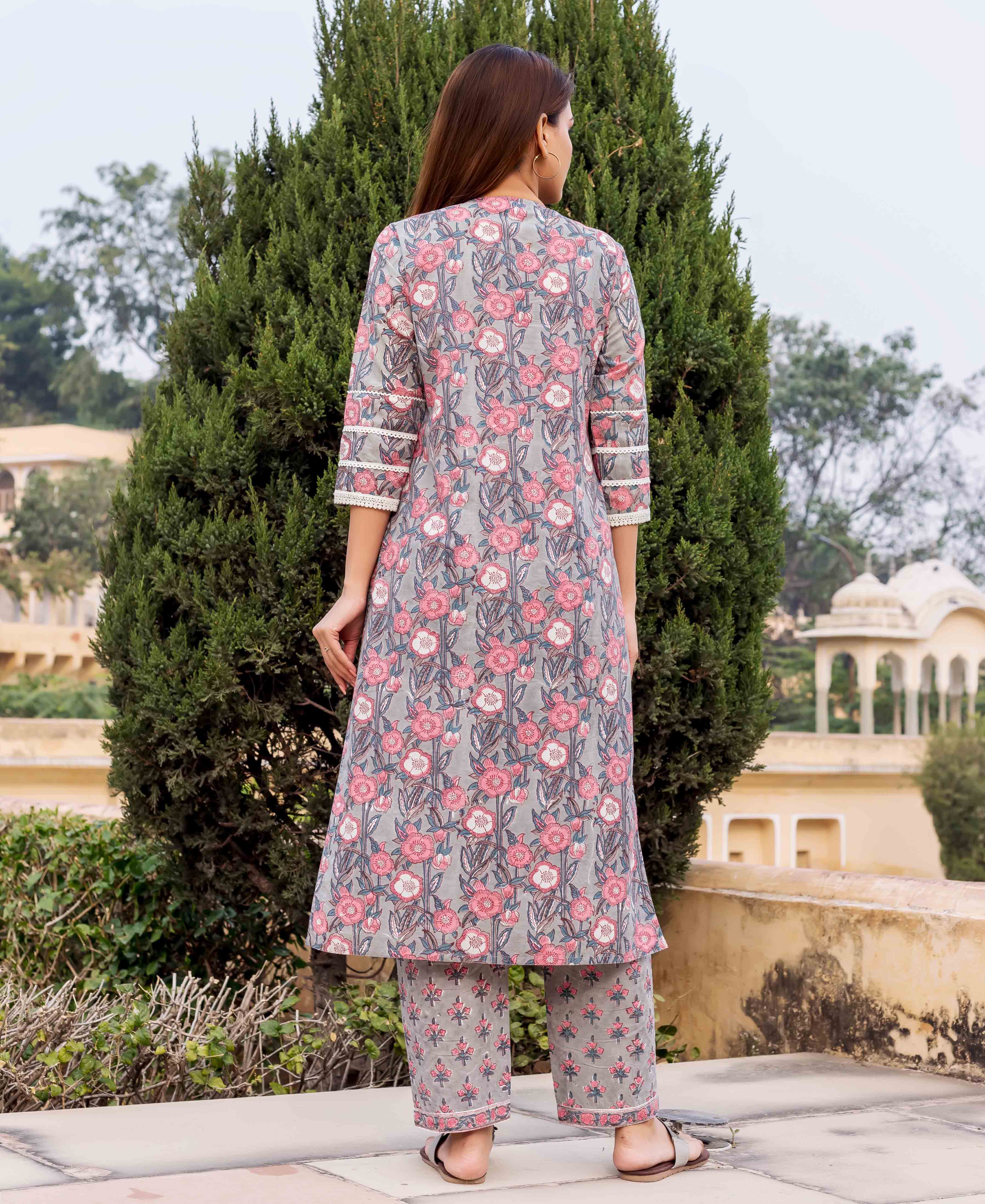 Back view of model in grey and pink hand block printed floral kurta with matching pants.
