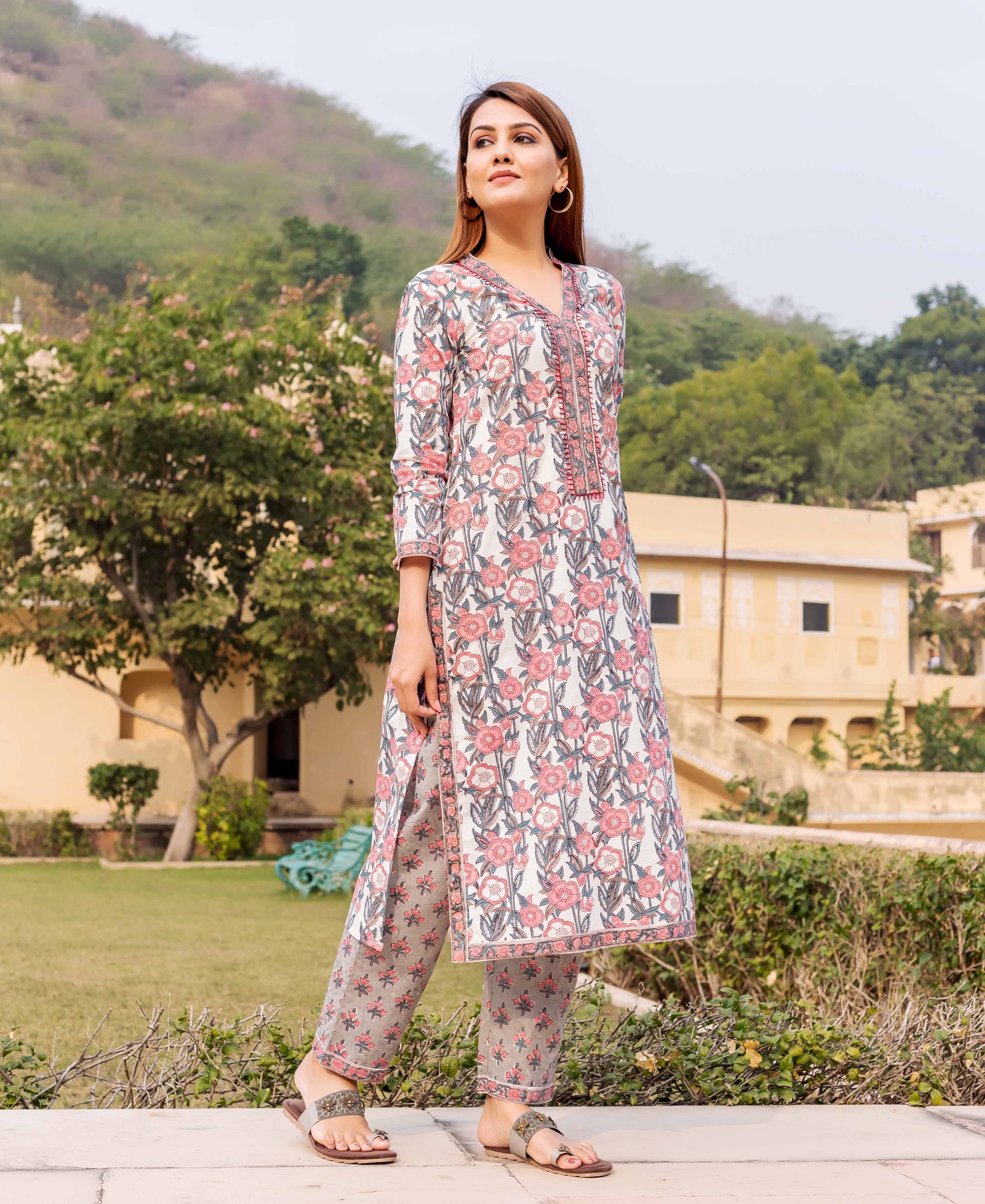 Woman in a white, pink, and grey hand block printed floral kurta set standing outdoors.