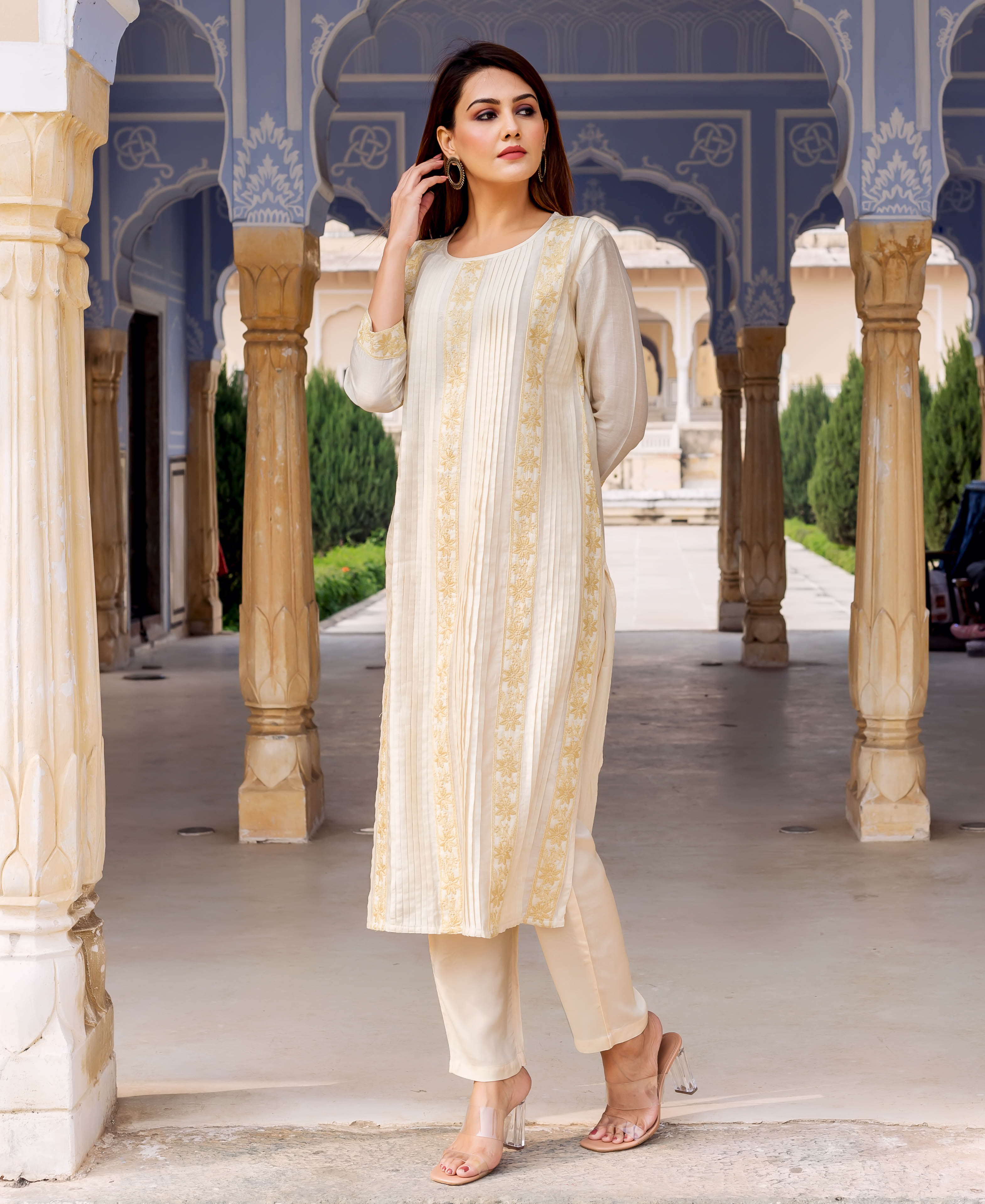 Model wearing an off-white straight kurta with vertical pintucks and gold floral embroidery.