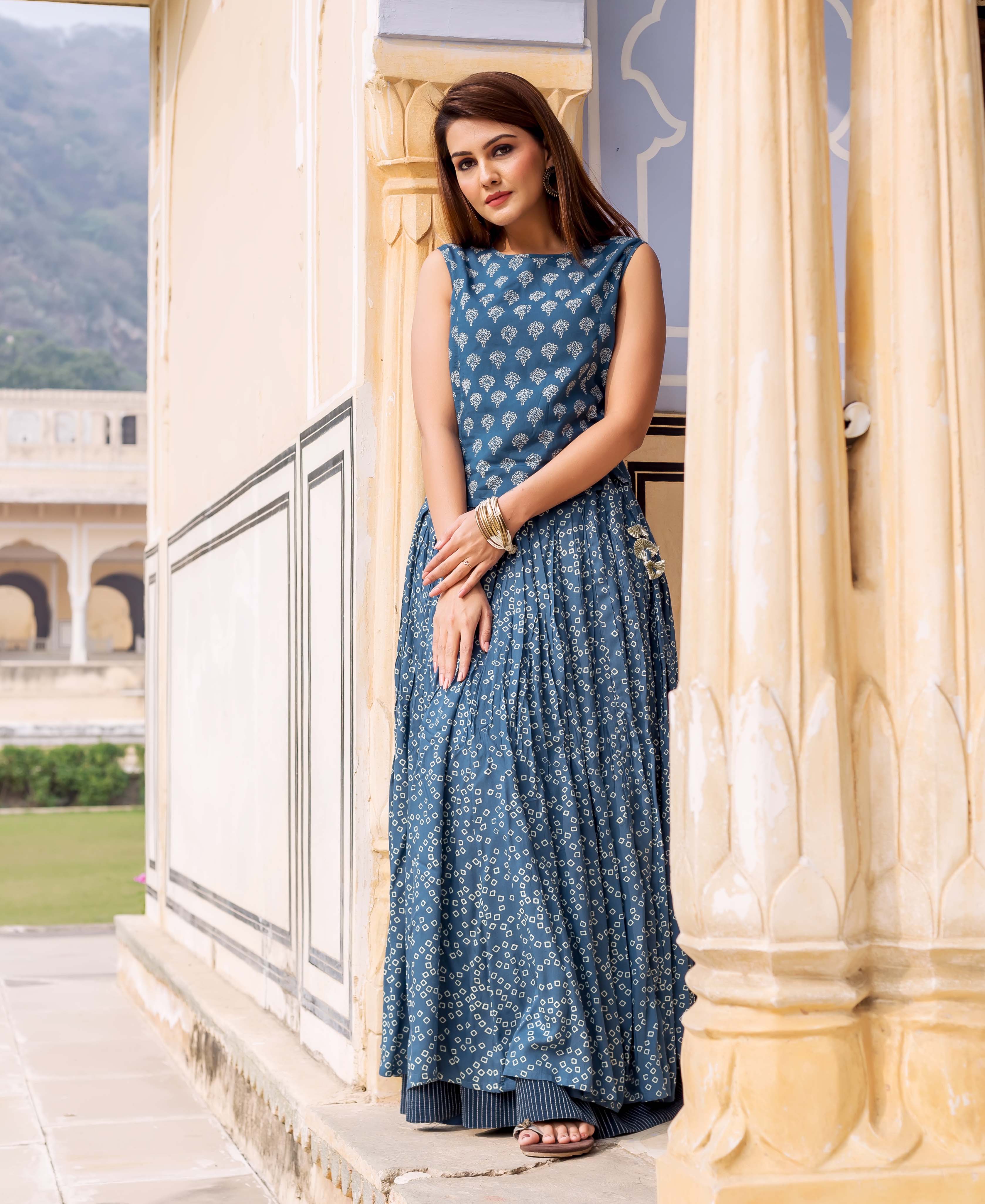 A woman in a long, indigo sleeveless top with white block print.