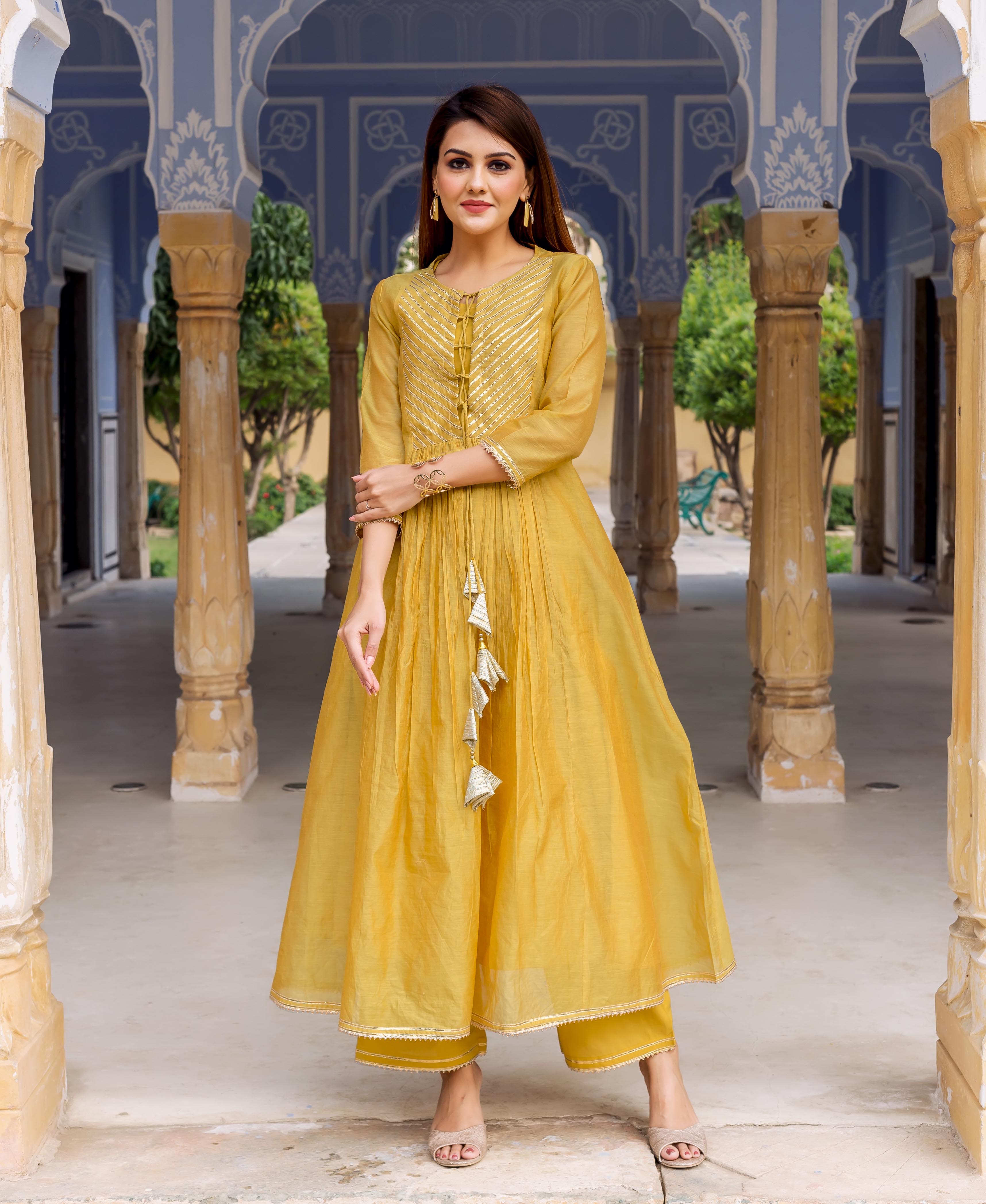 Front view of model wearing honey yellow ethnic kurta with golden gotta work and matching bottoms.
