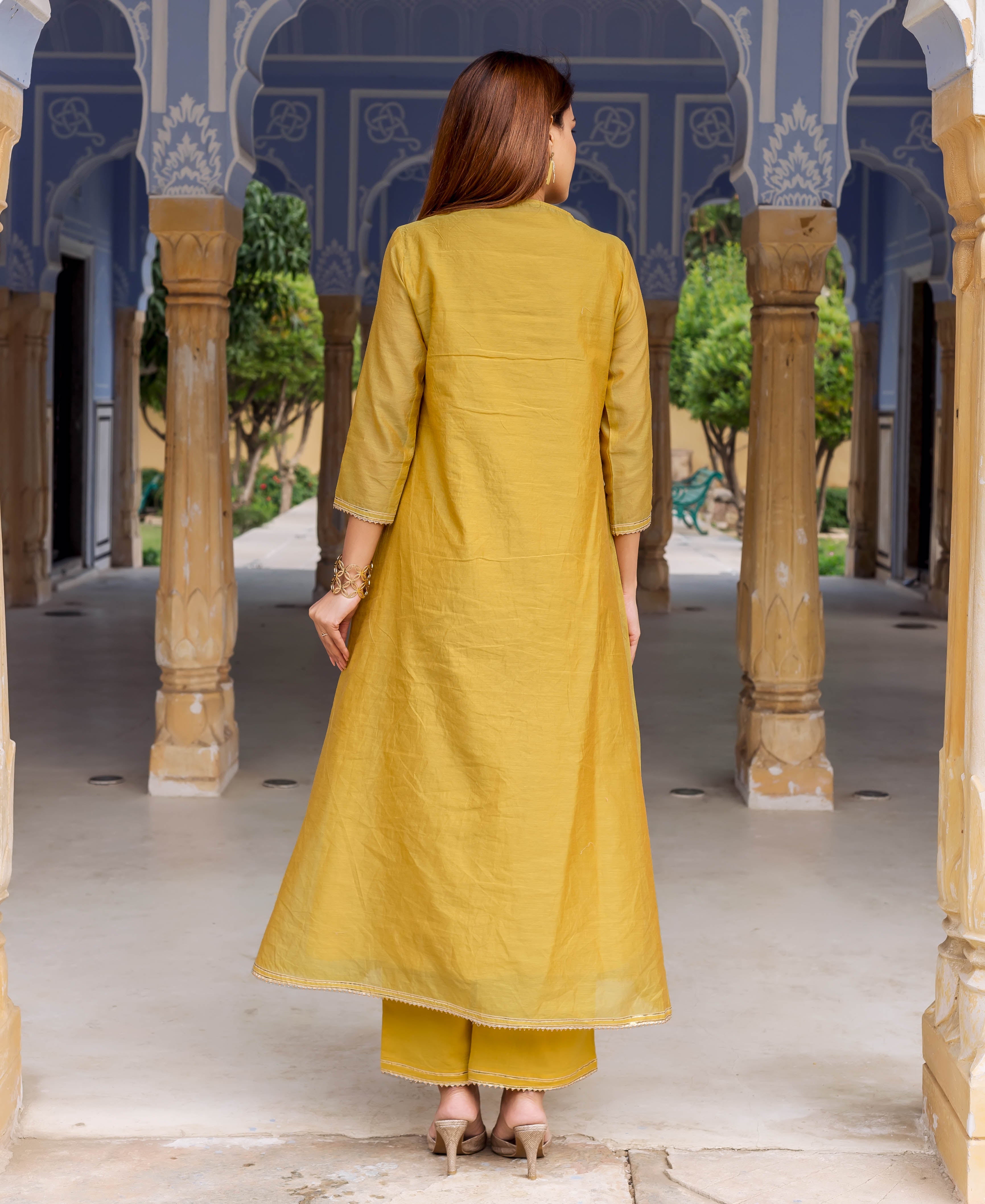 A woman in a long, honey yellow kurta with intricate white block print.